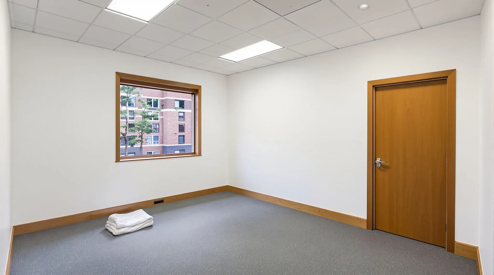 Empty strata office suite after make good, with painted walls, original ceiling tiles, carpet tiles and a timber door