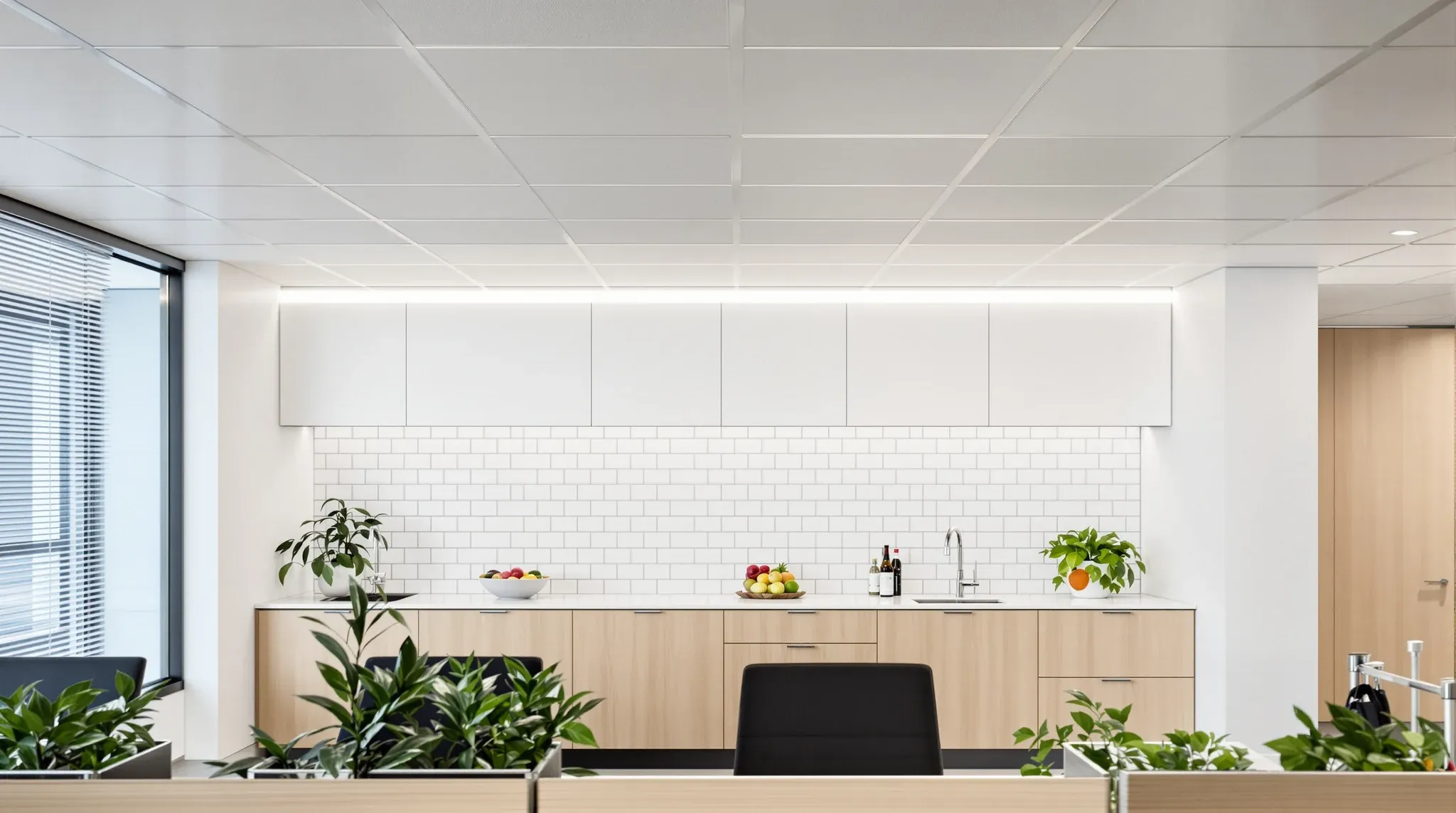 An office kitchenette under smooth white ceiling tiles, with textured tiles continuing over the desks