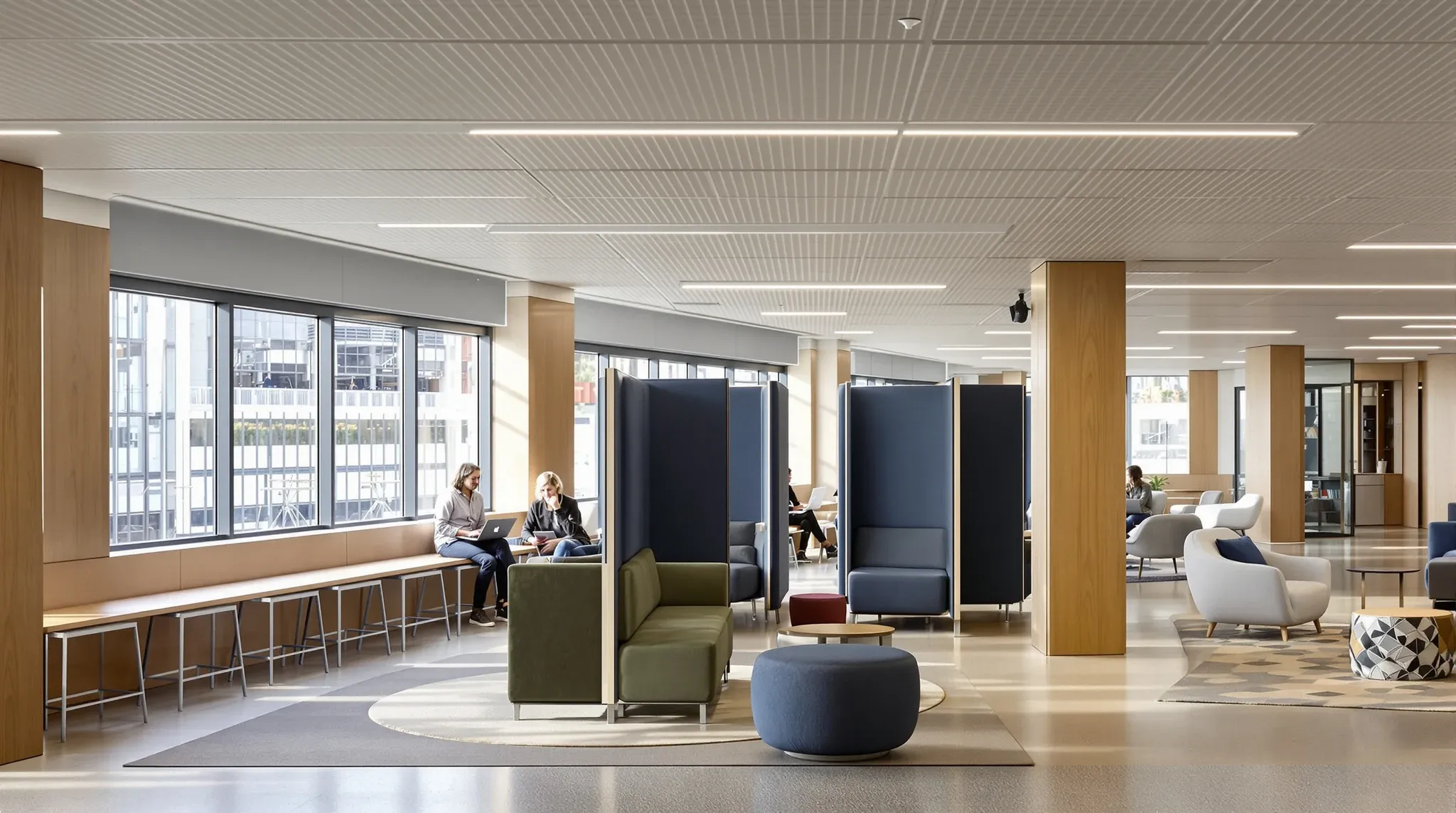 An activity-based office floor with a high bench, booths and a lounge, people small and blurred