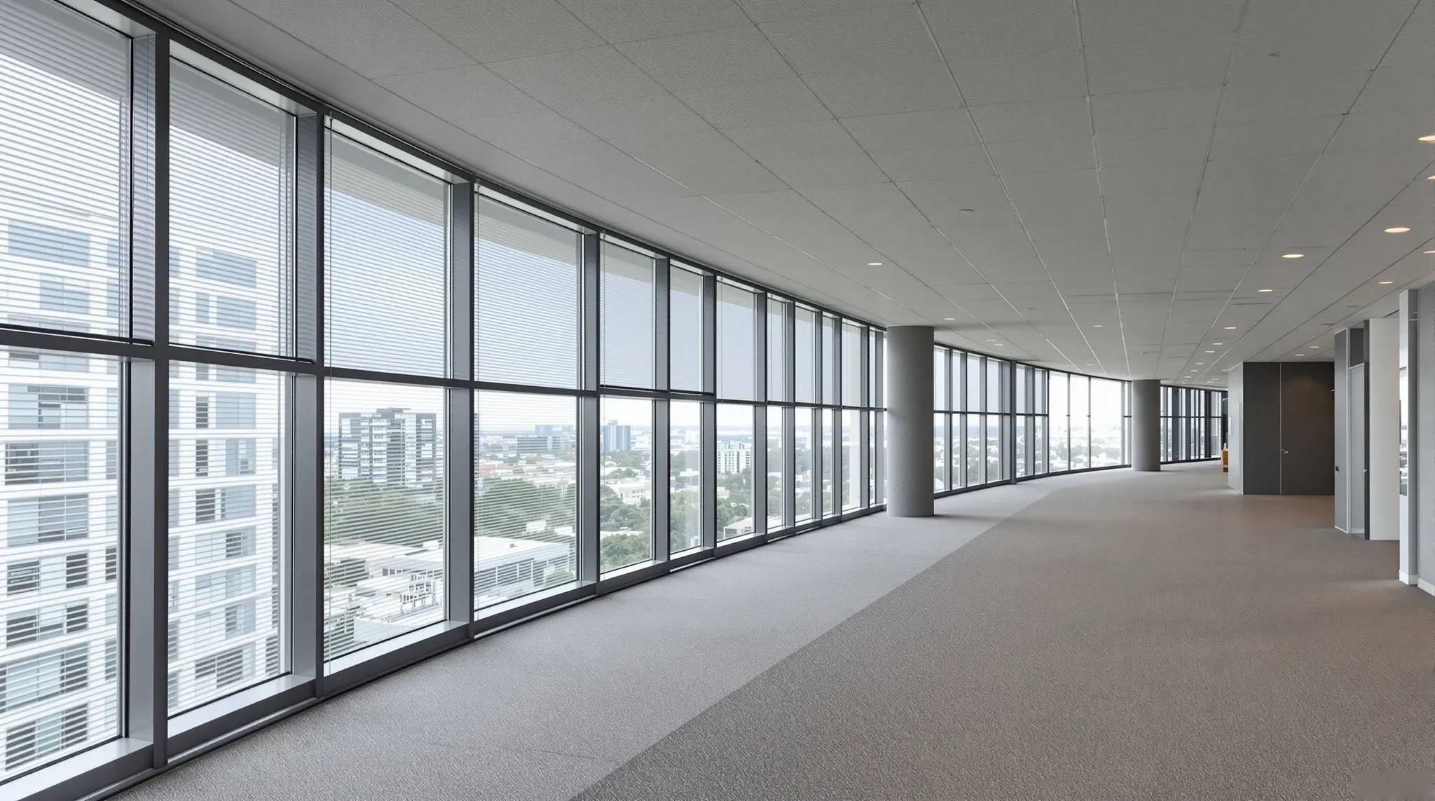 A wide clear walkway along the windows of an office floor, with meeting rooms set back from it