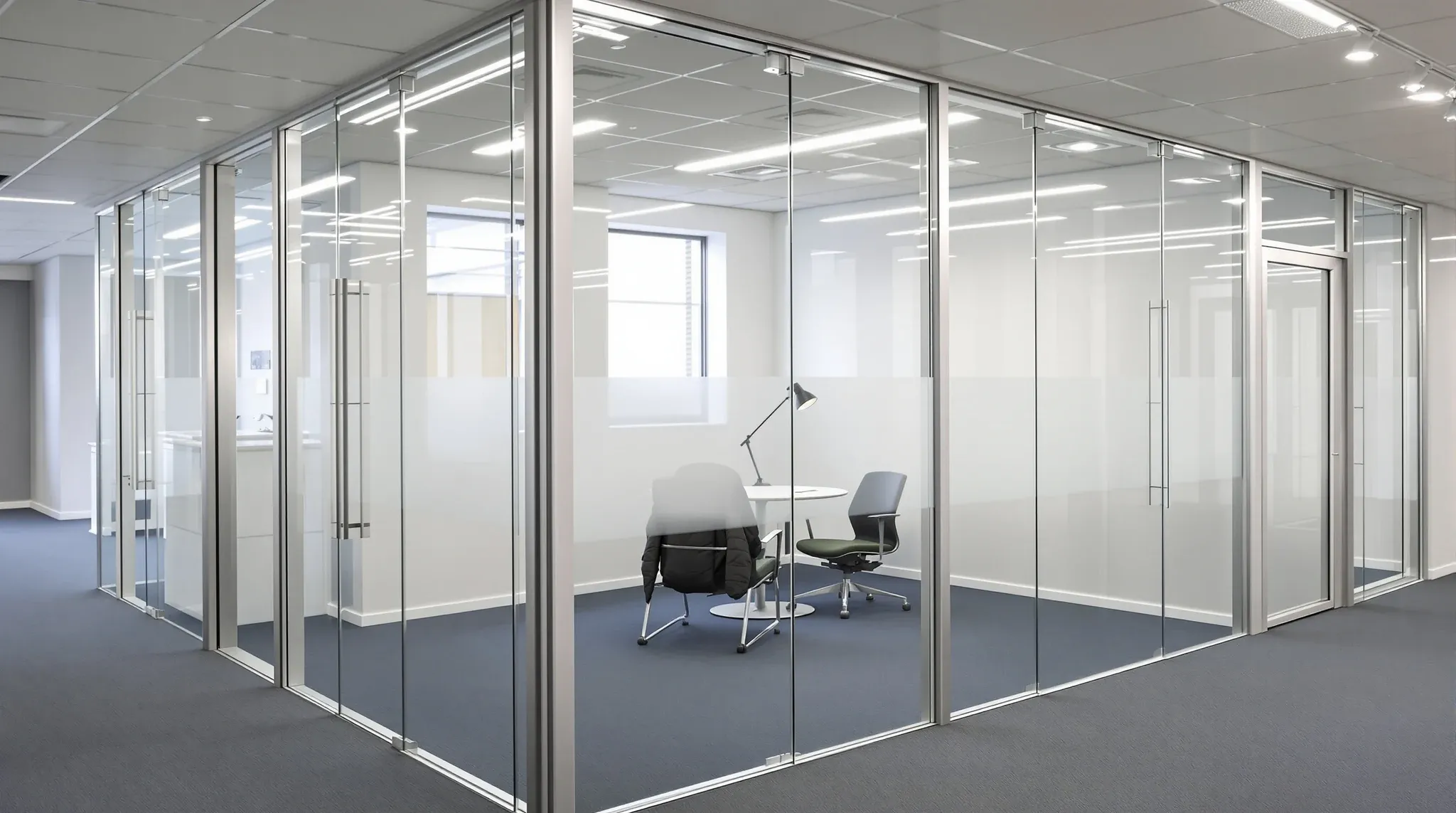 A slim aluminium-framed glass office front meeting a frameless glass run with a clear joint