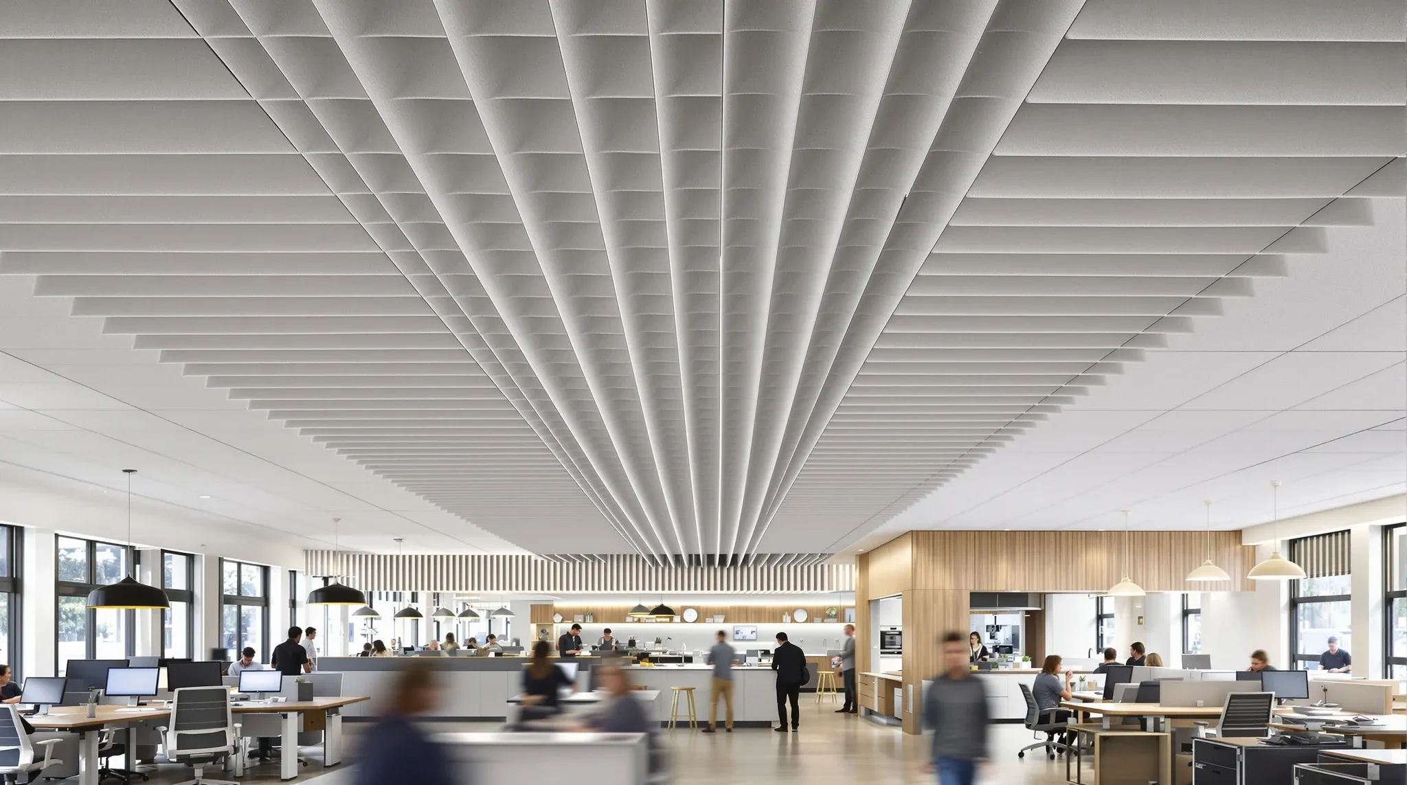 A long open-plan office with an acoustic tile ceiling and felt baffles over the kitchen