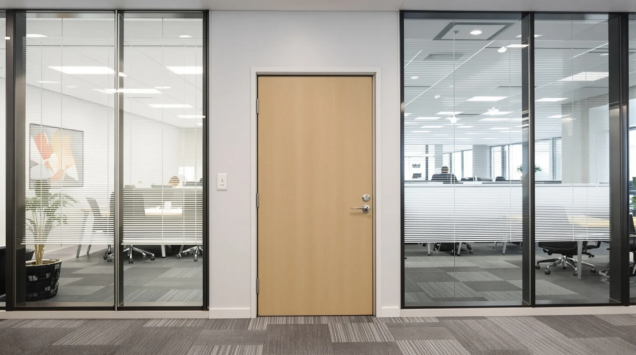 A quiet closed private office beside a busy open plan floor through glass