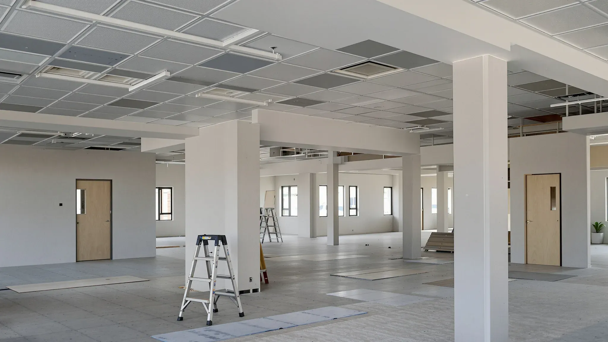 Office floor part way through its fitout, with new walls and doors, a partly filled ceiling grid and a ladder