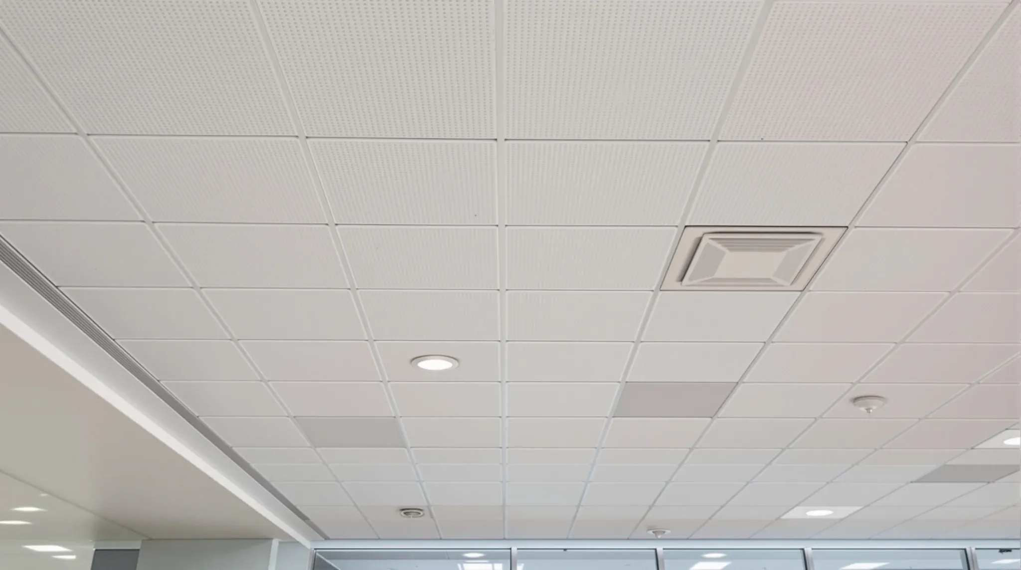 Looking straight up at an office ceiling with lights, sprinklers, detectors and diffusers set out in a neat grid