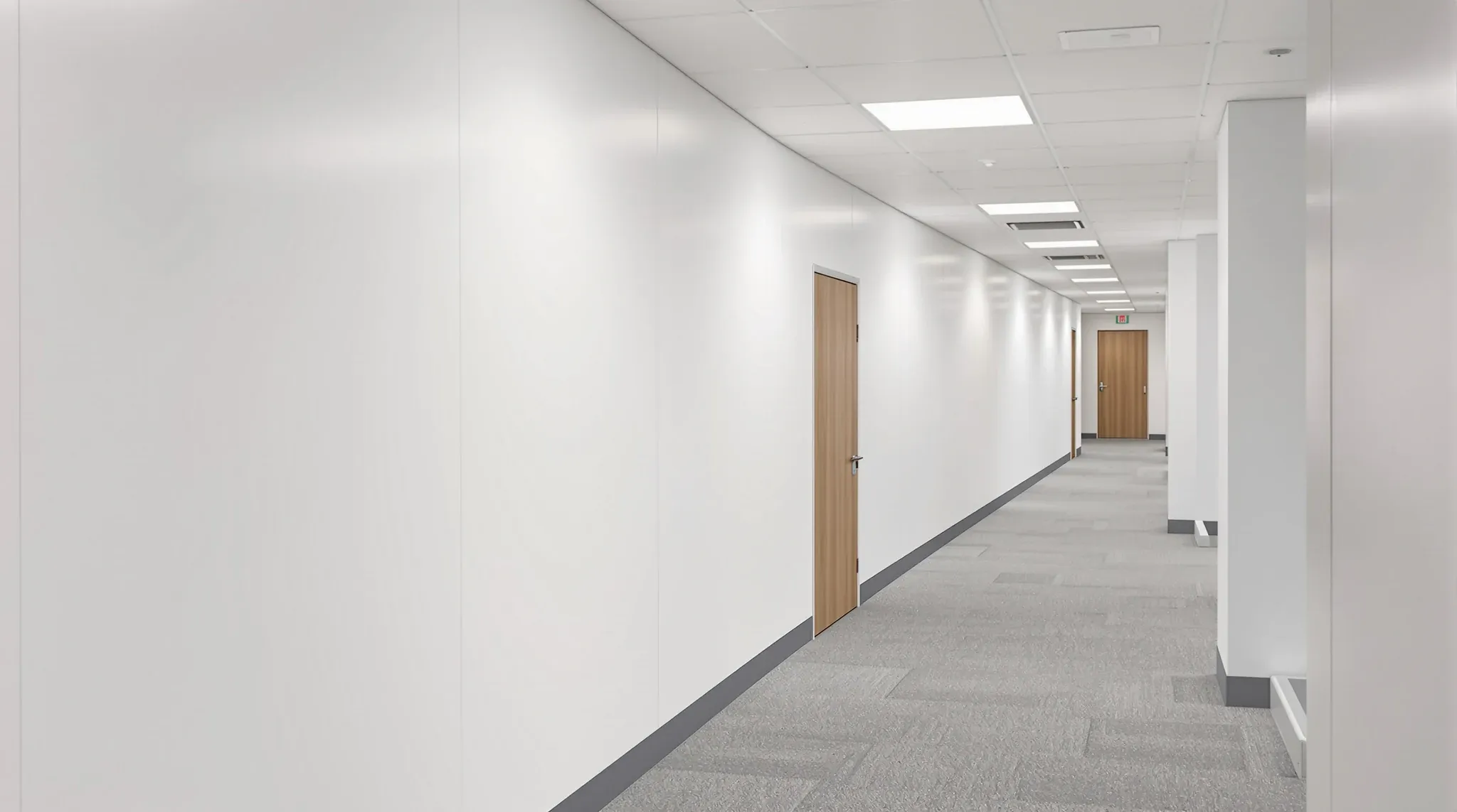 A long finished painted plasterboard partition wall running down an office corridor