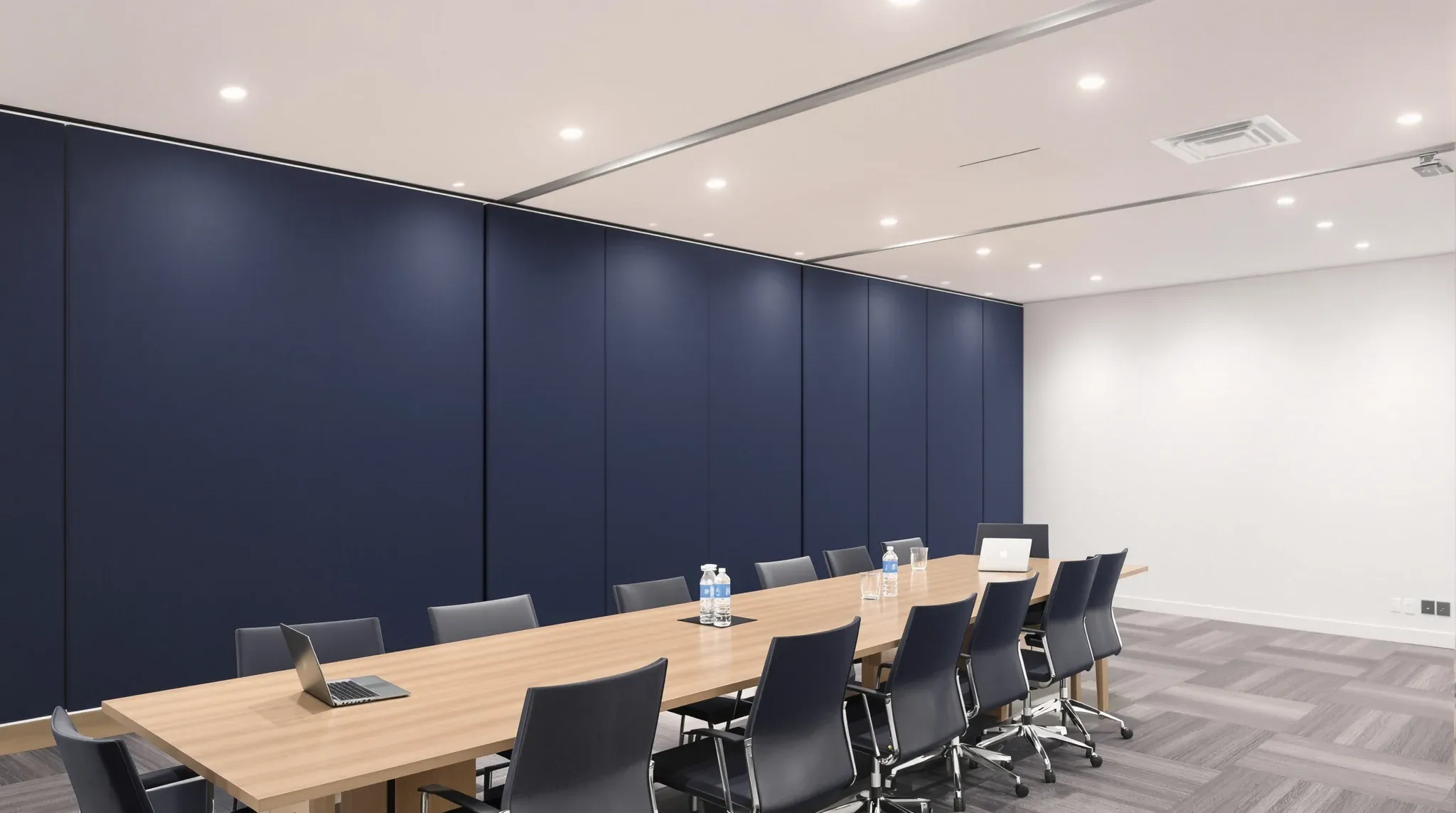 An enclosed solid-walled boardroom with a wall of fabric acoustic panels and a long timber table
