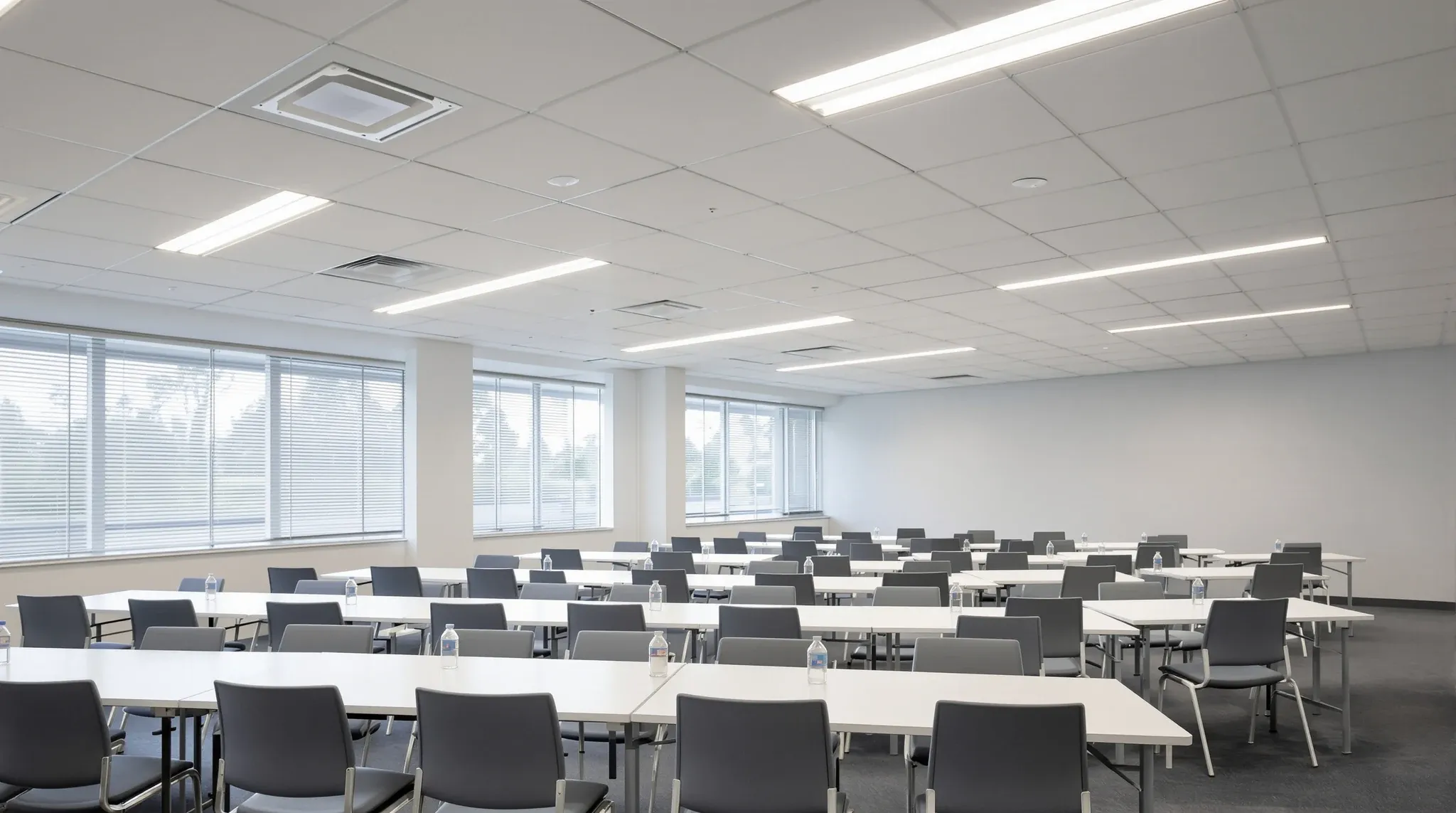 A training room with rows of tables under a ceiling of long rectangular white tiles all running one way