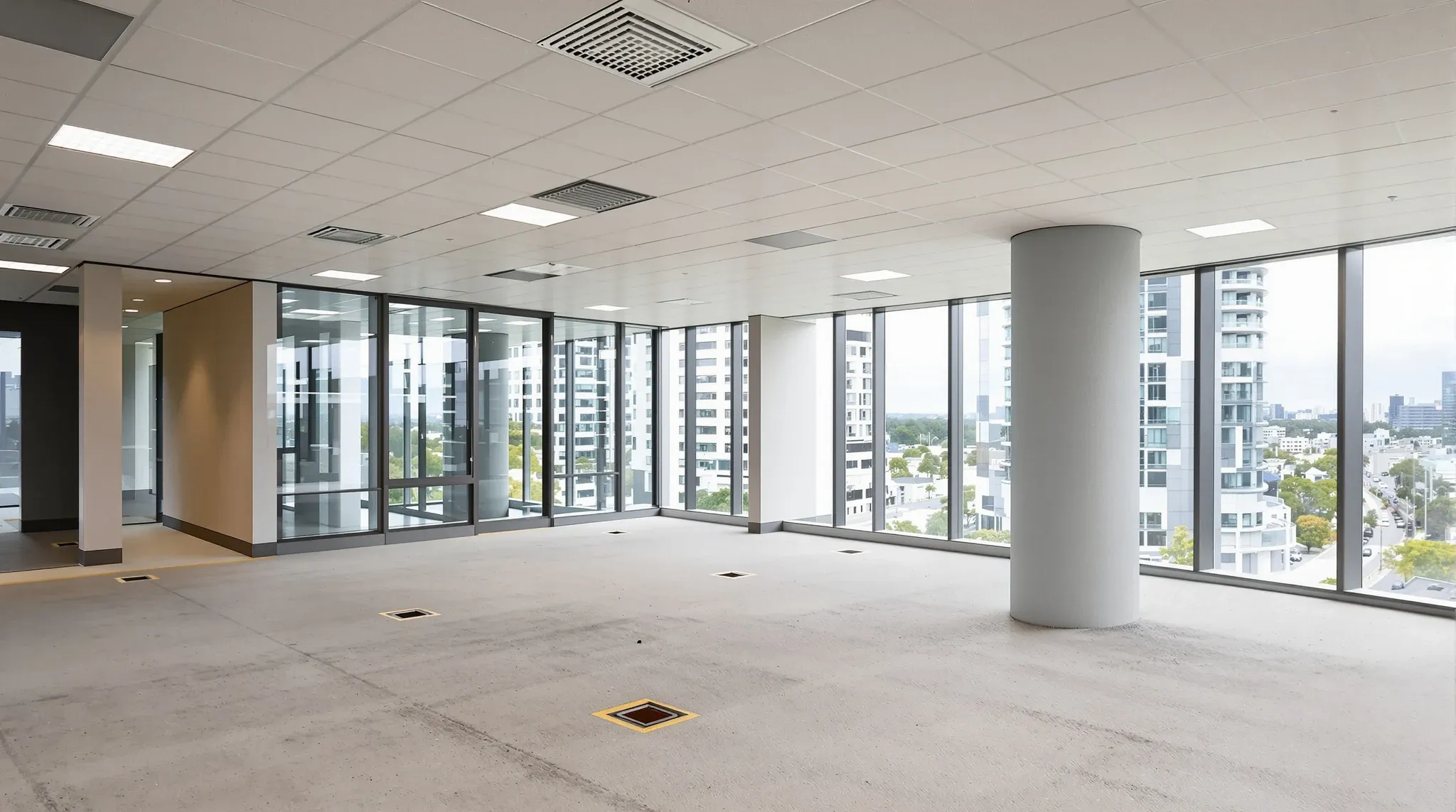 A new office floor in base building condition with a bare concrete floor, grid ceiling and no fitout