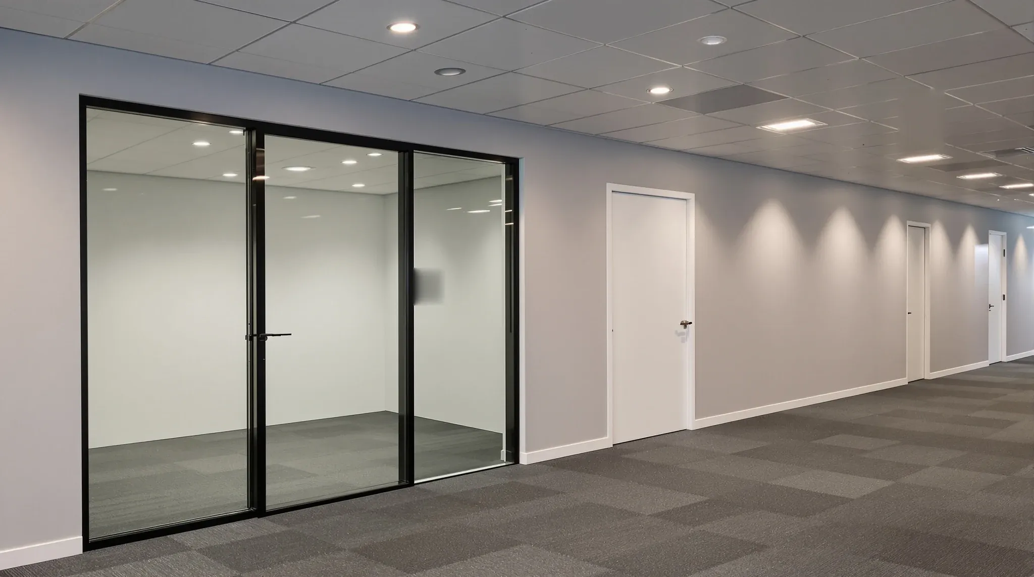 A nearly finished office fitout with a glass meeting room, a plasterboard office and floor protection still down