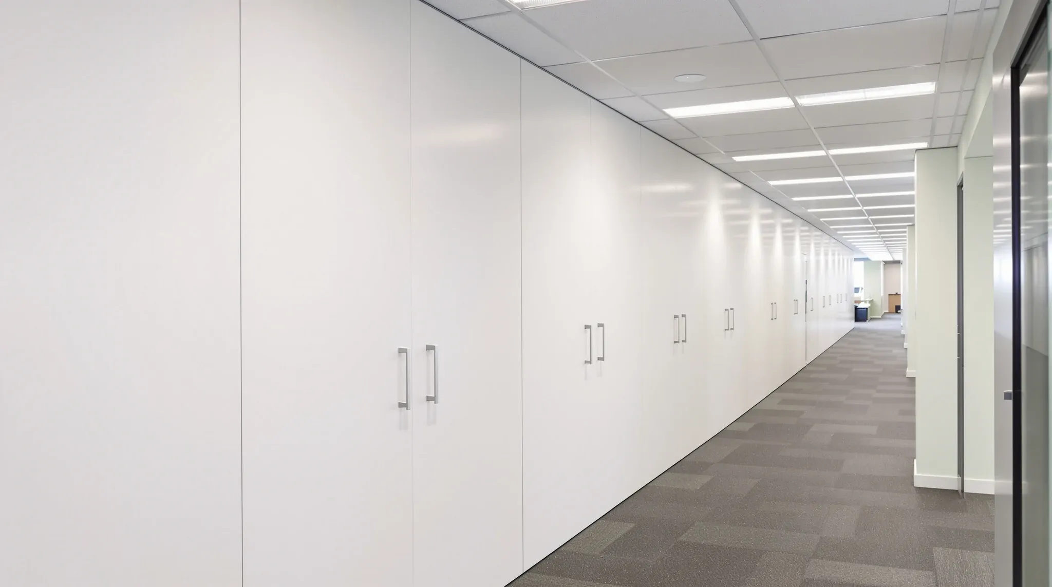 A storage wall built along a solid tenancy boundary wall beside a walkway