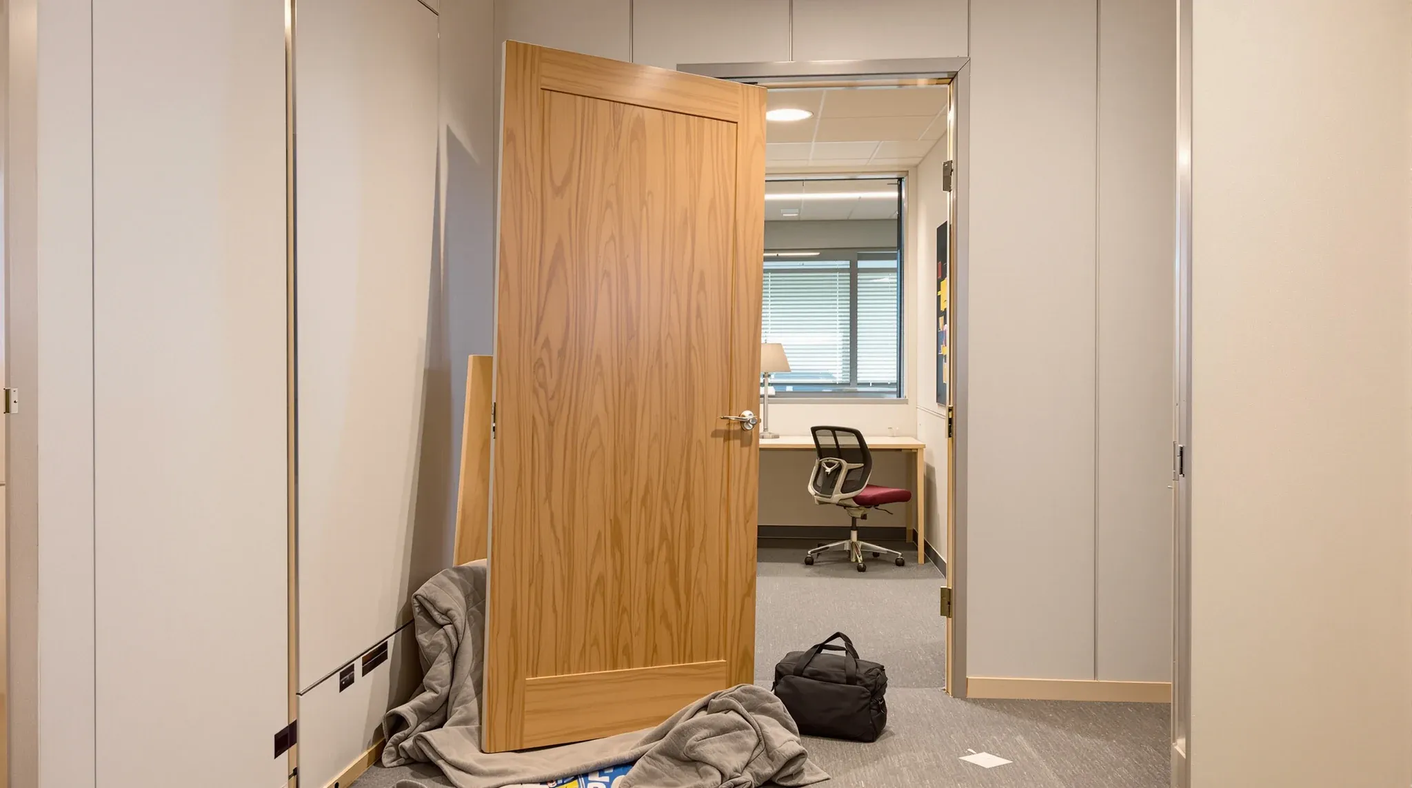 An office door lifted off its hinges and resting on a padded blanket beside its empty frame