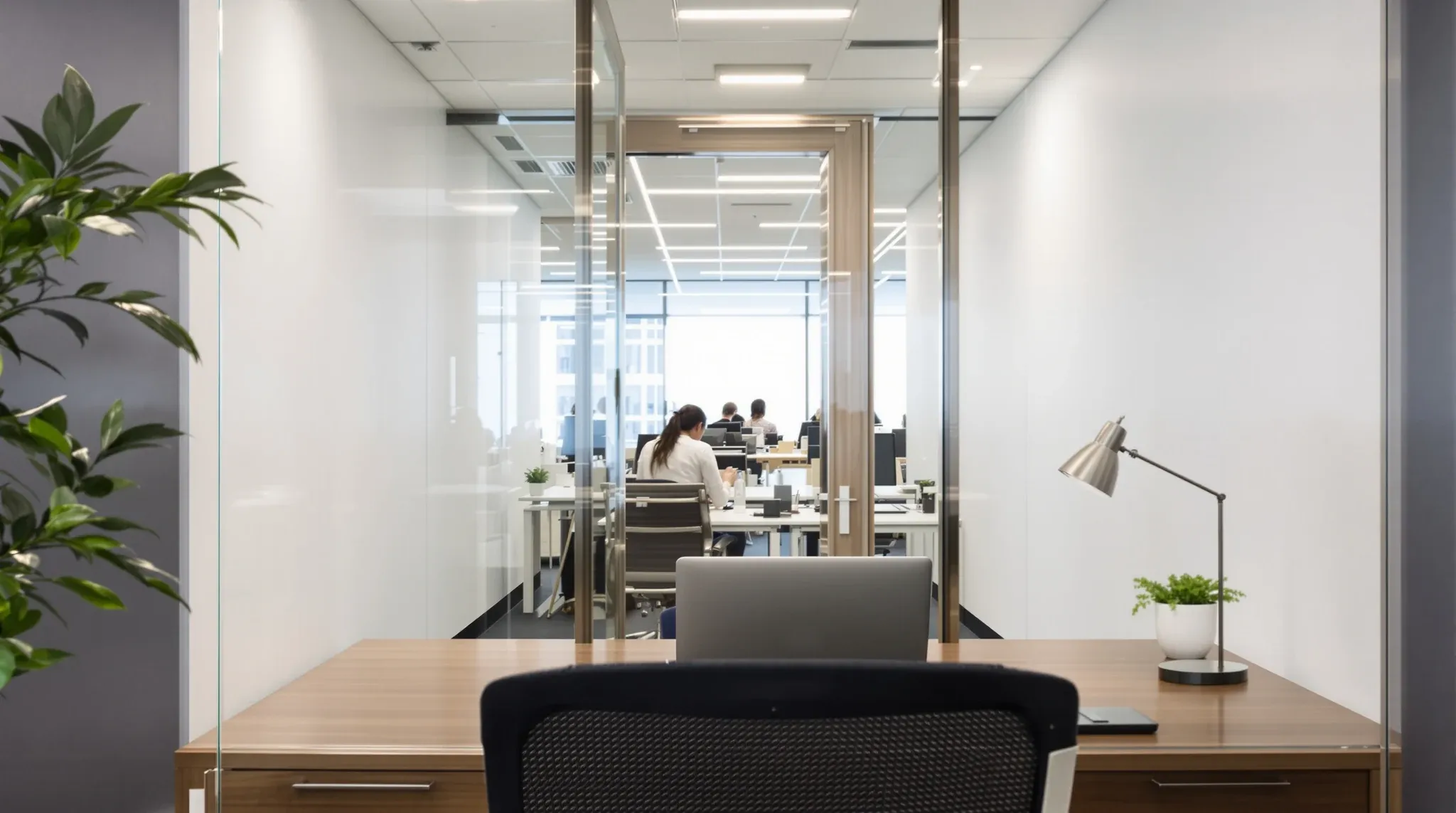 Looking out from a desk inside a glass private office, through its glass front and door to the open floor