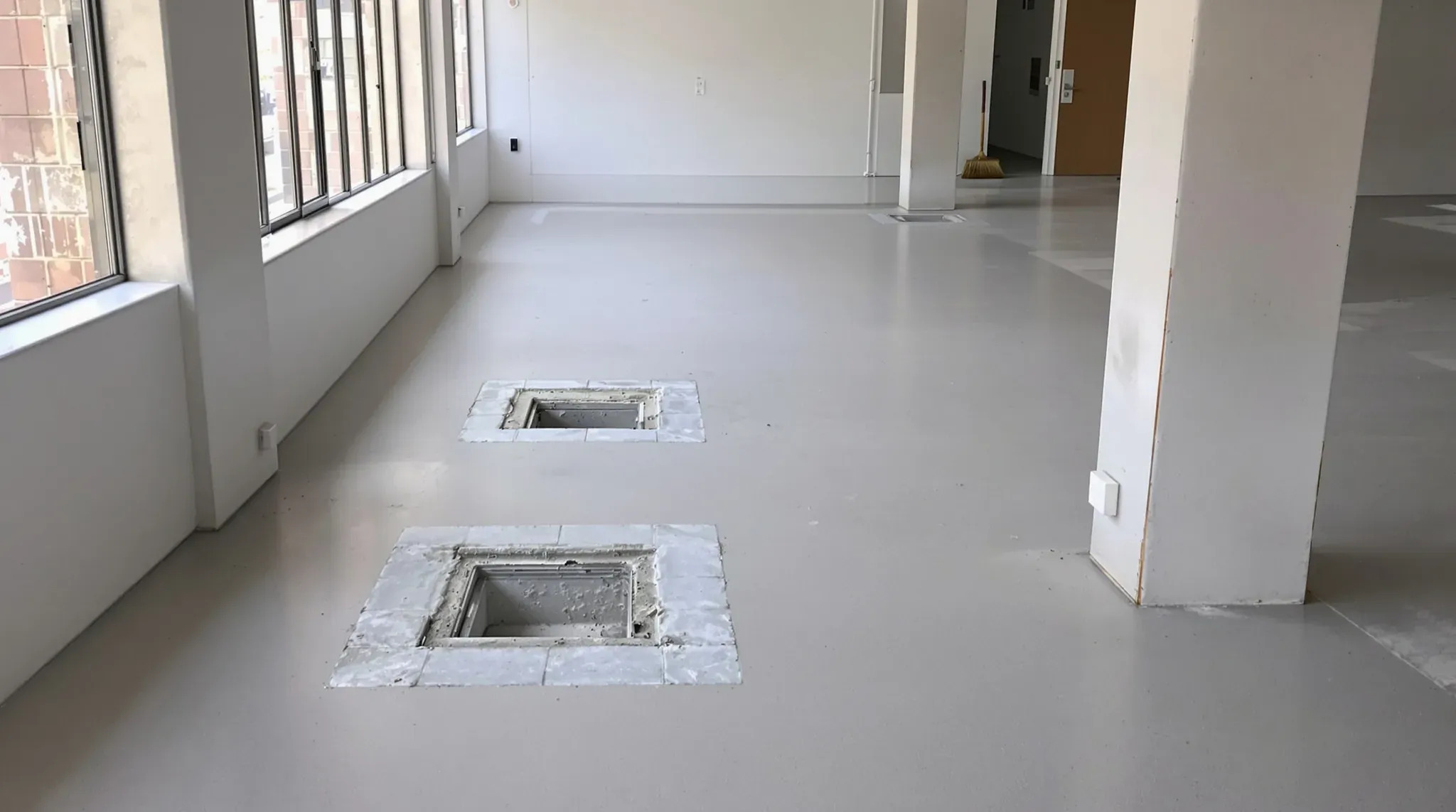 Office floor at handback with carpet lifted to bare screed and two open floor box recesses to be filled