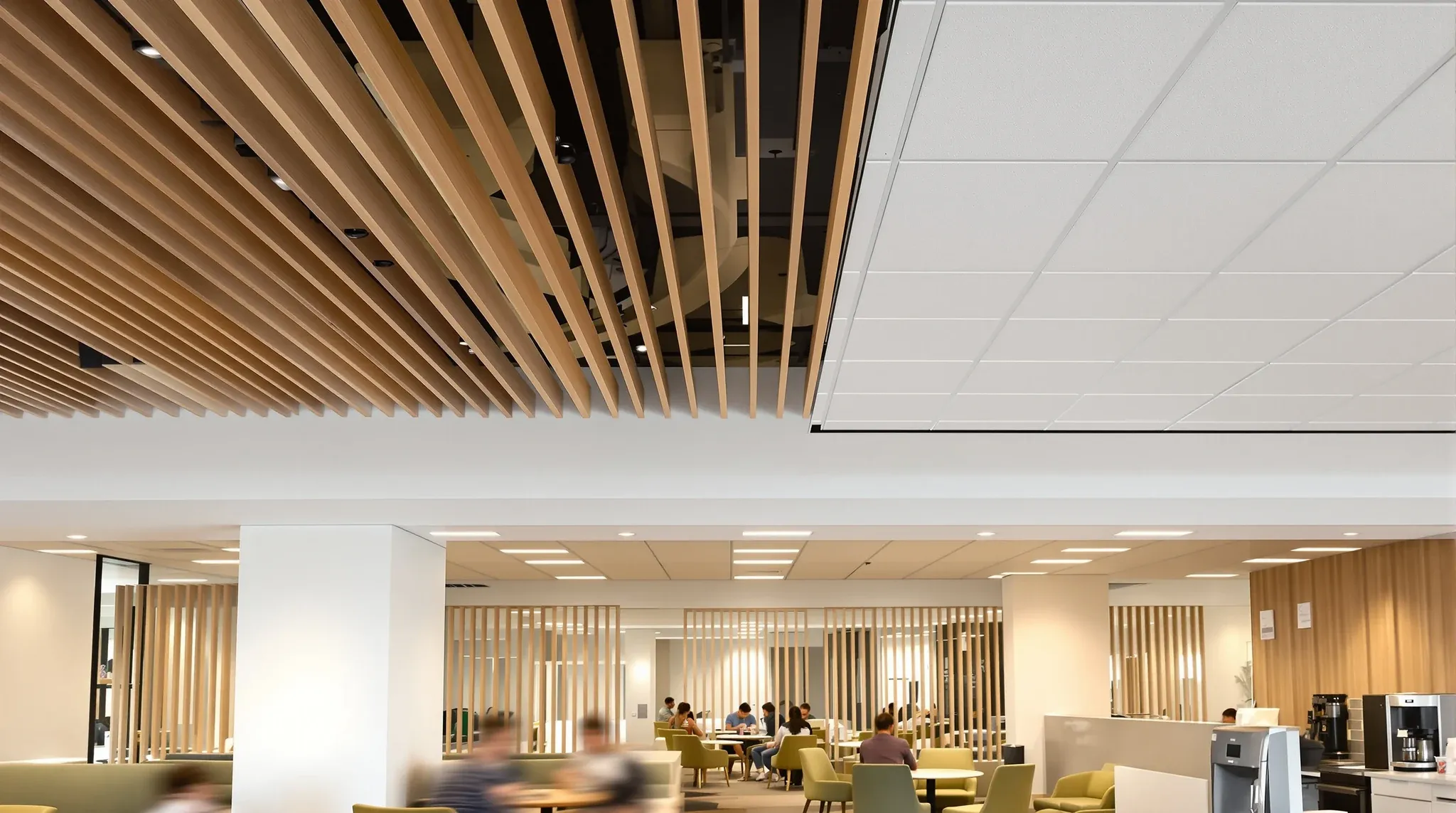 A staff lounge where a timber slat ceiling meets a plasterboard bulkhead and a white tiled ceiling beyond