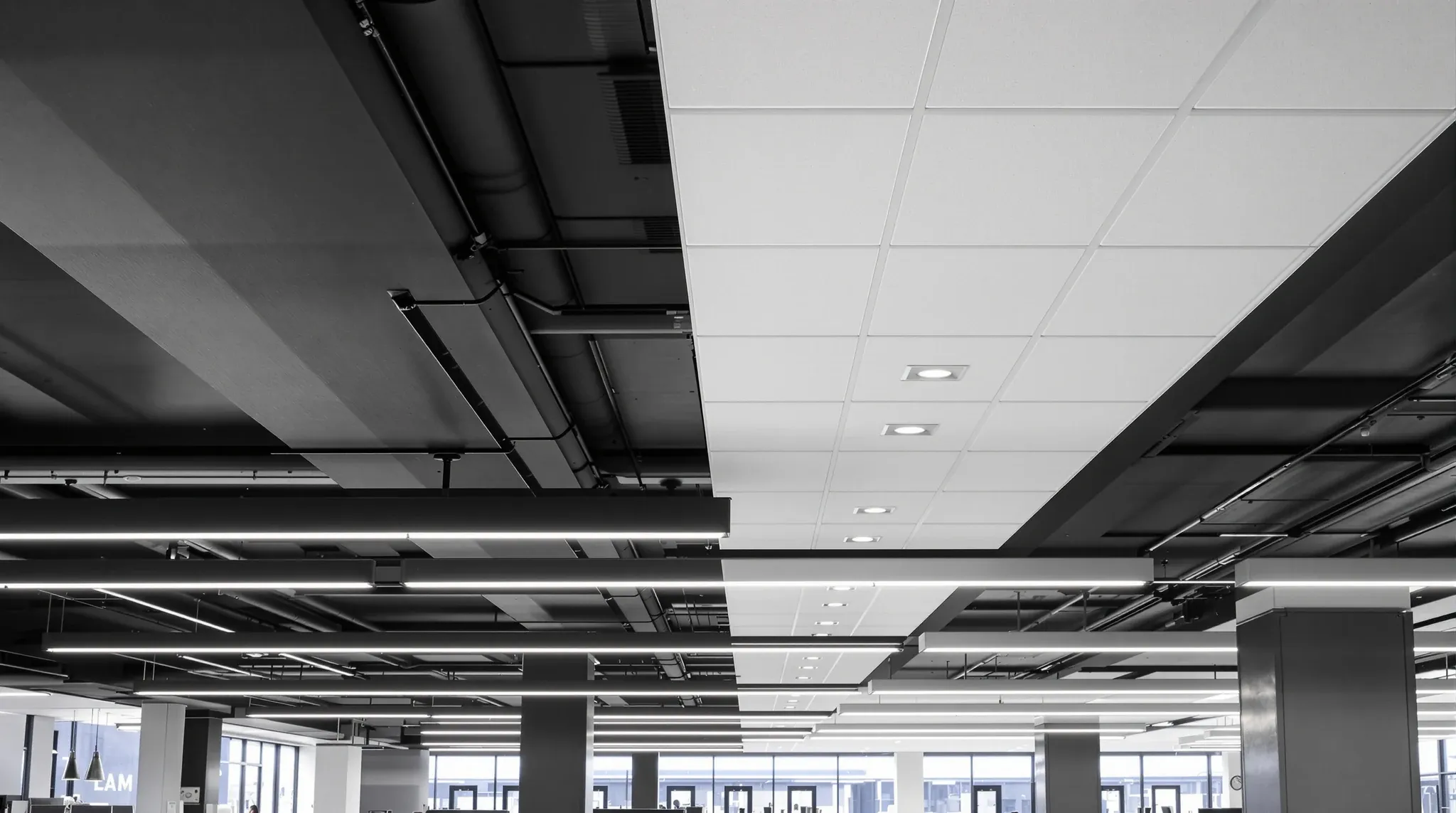 An office ceiling changing from black exposed services to a white tiled ceiling