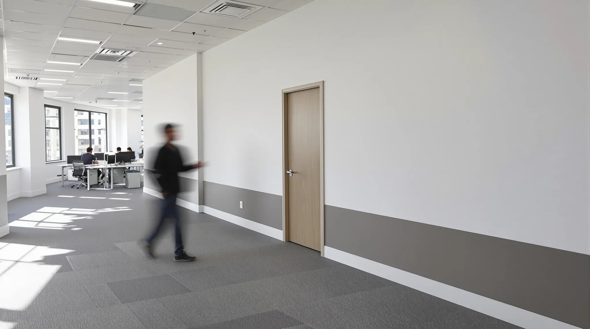 A newly built office wall with a fresh door beside occupied desks after a weekend reconfiguration