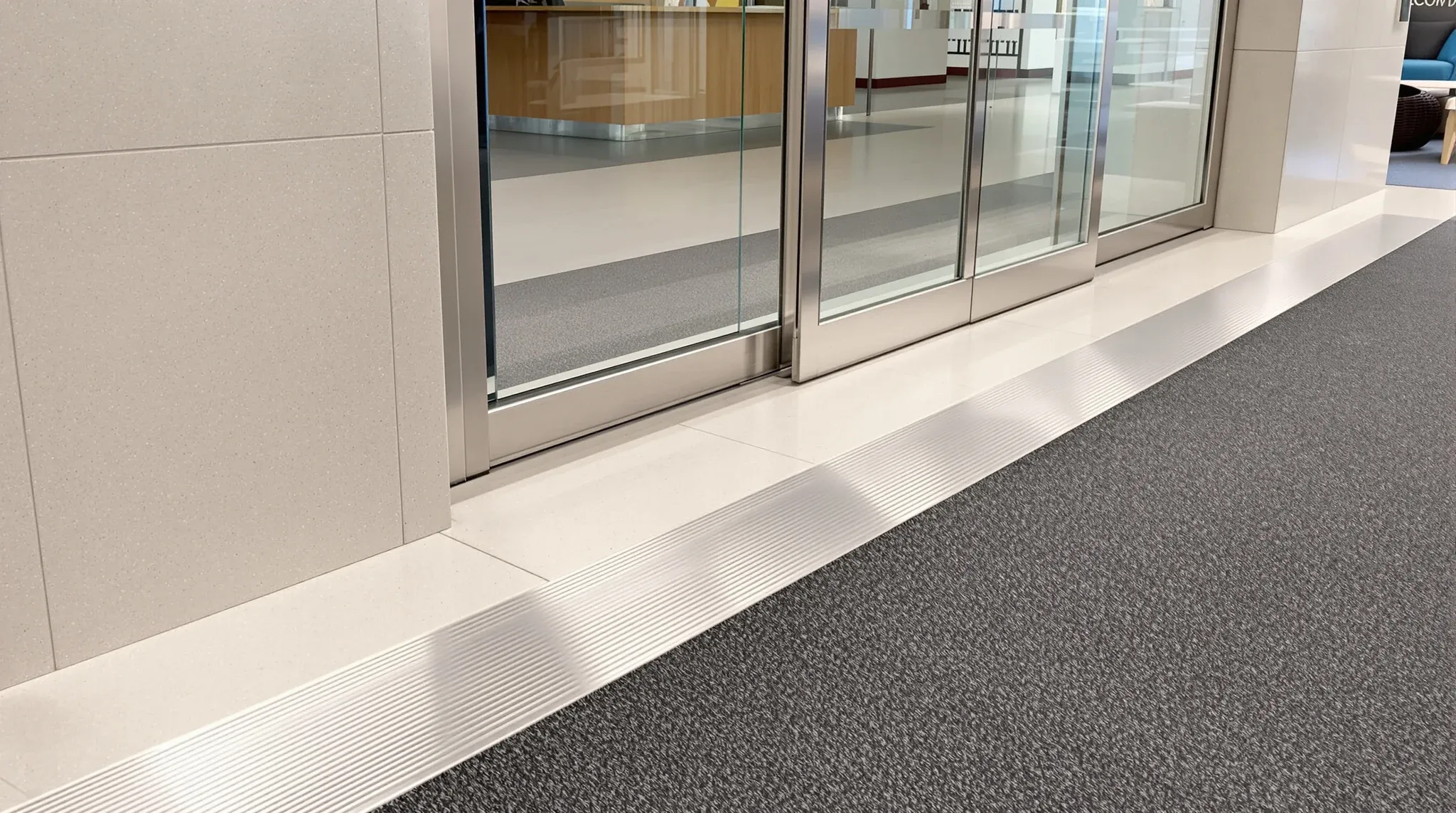 The threshold where a building lift lobby floor meets the carpet of an office tenancy