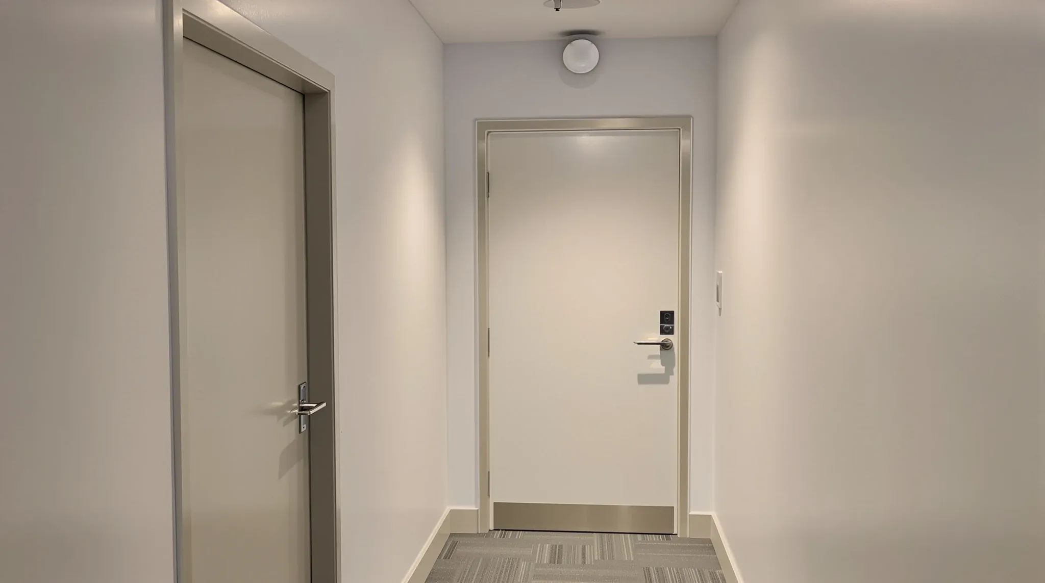 A new plasterboard office corridor ending at a plain solid door with a closer, shut
