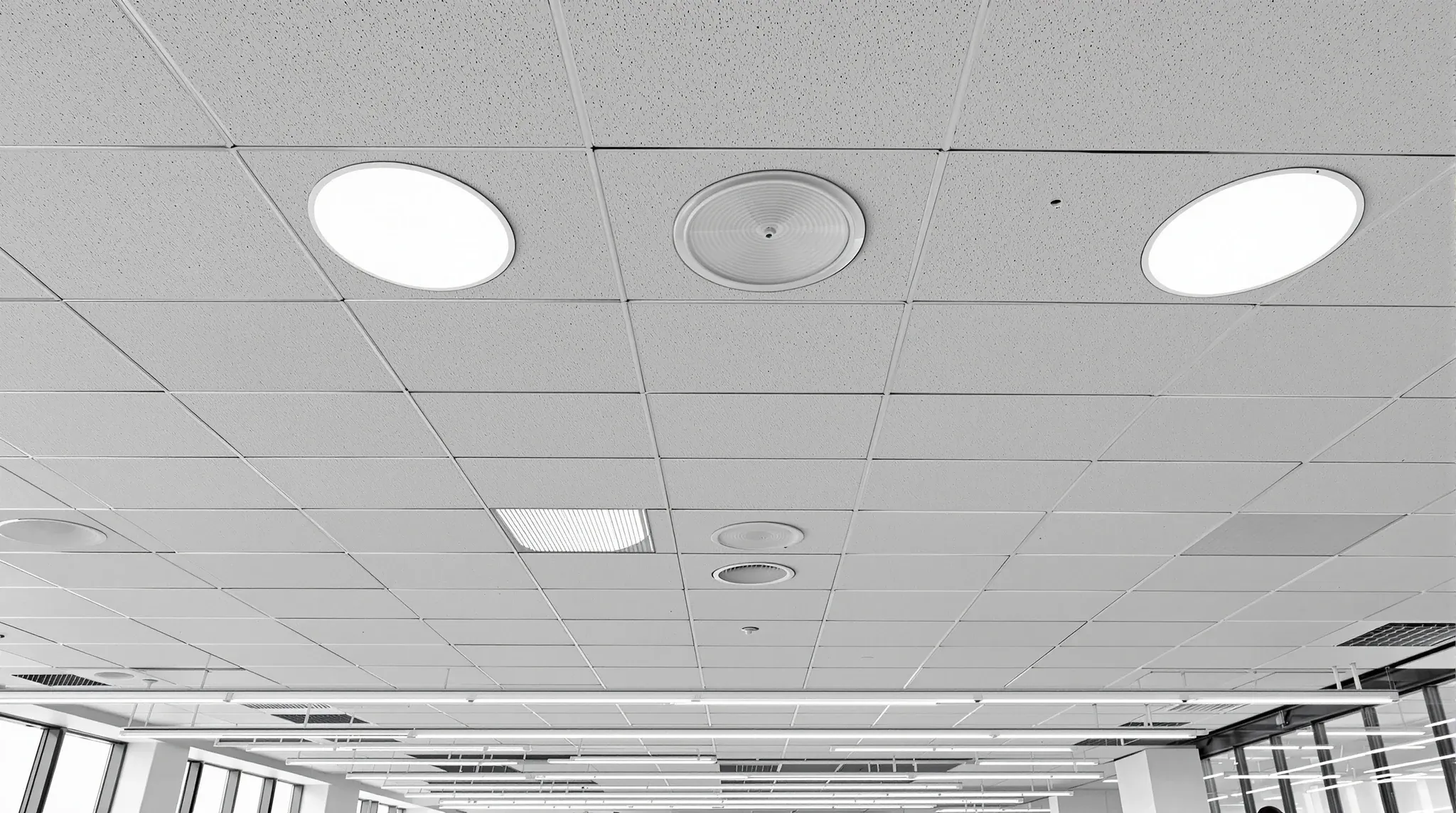 A wide view of an office ceiling with round and slot air diffusers