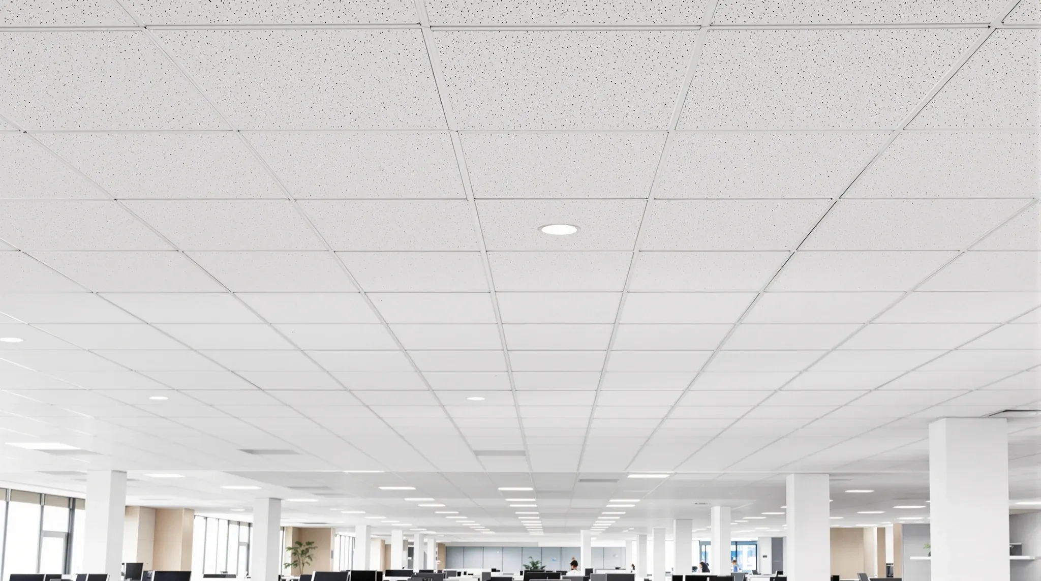 A wide view of a finished office ceiling with uniform plain acoustic tiles