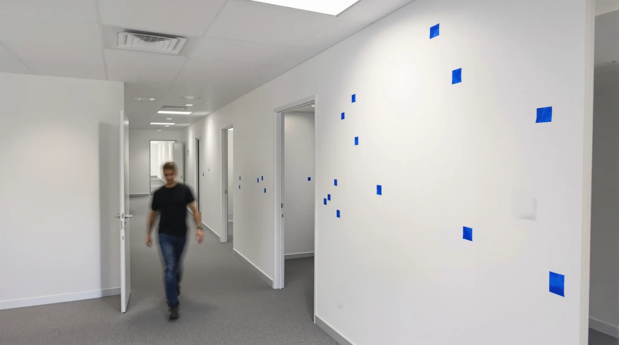 Newly painted office walls with small squares of blue tape marking defects before handover