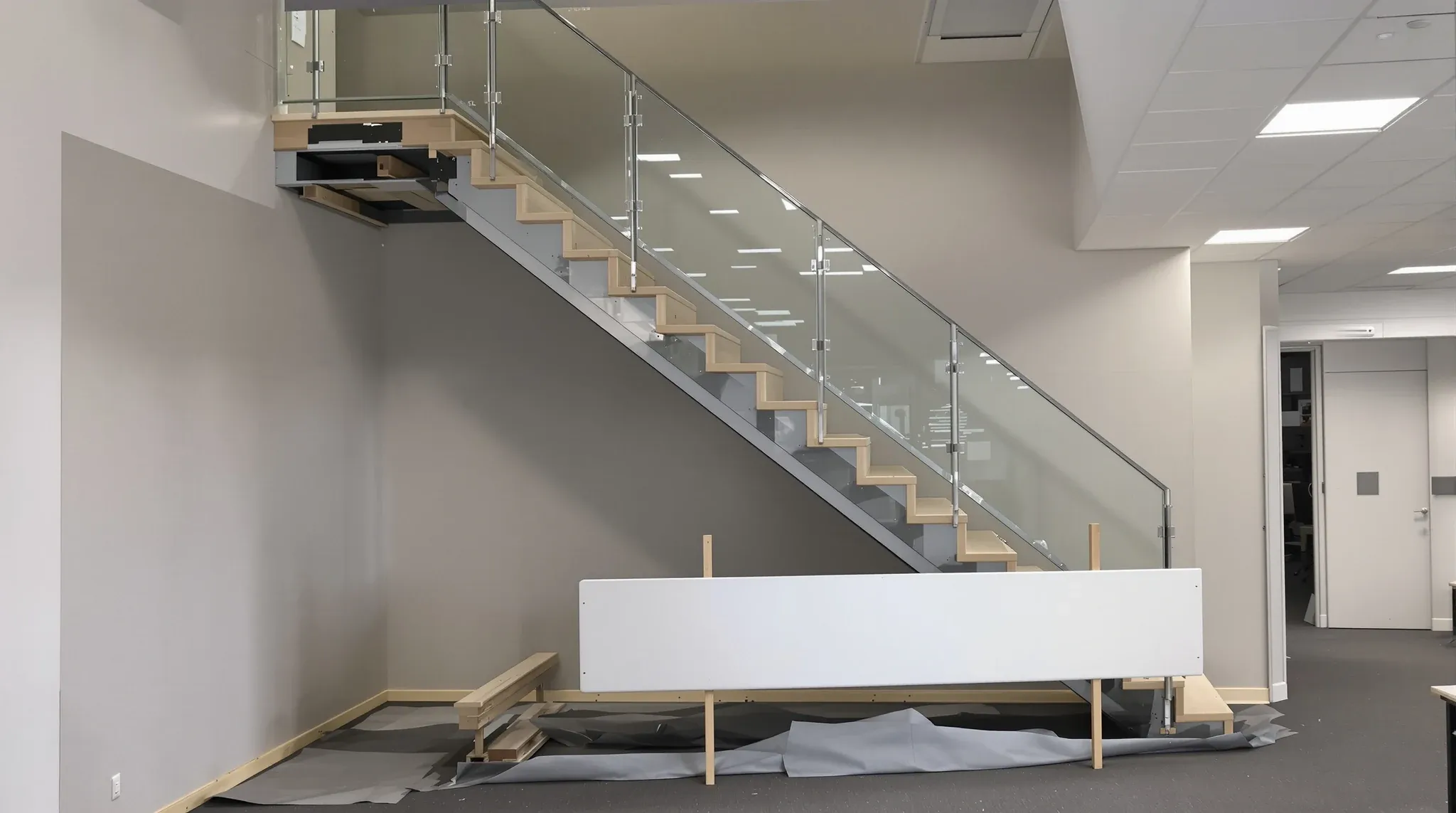 An internal office stair closed off at the start of its removal, with the glass balustrade taken out