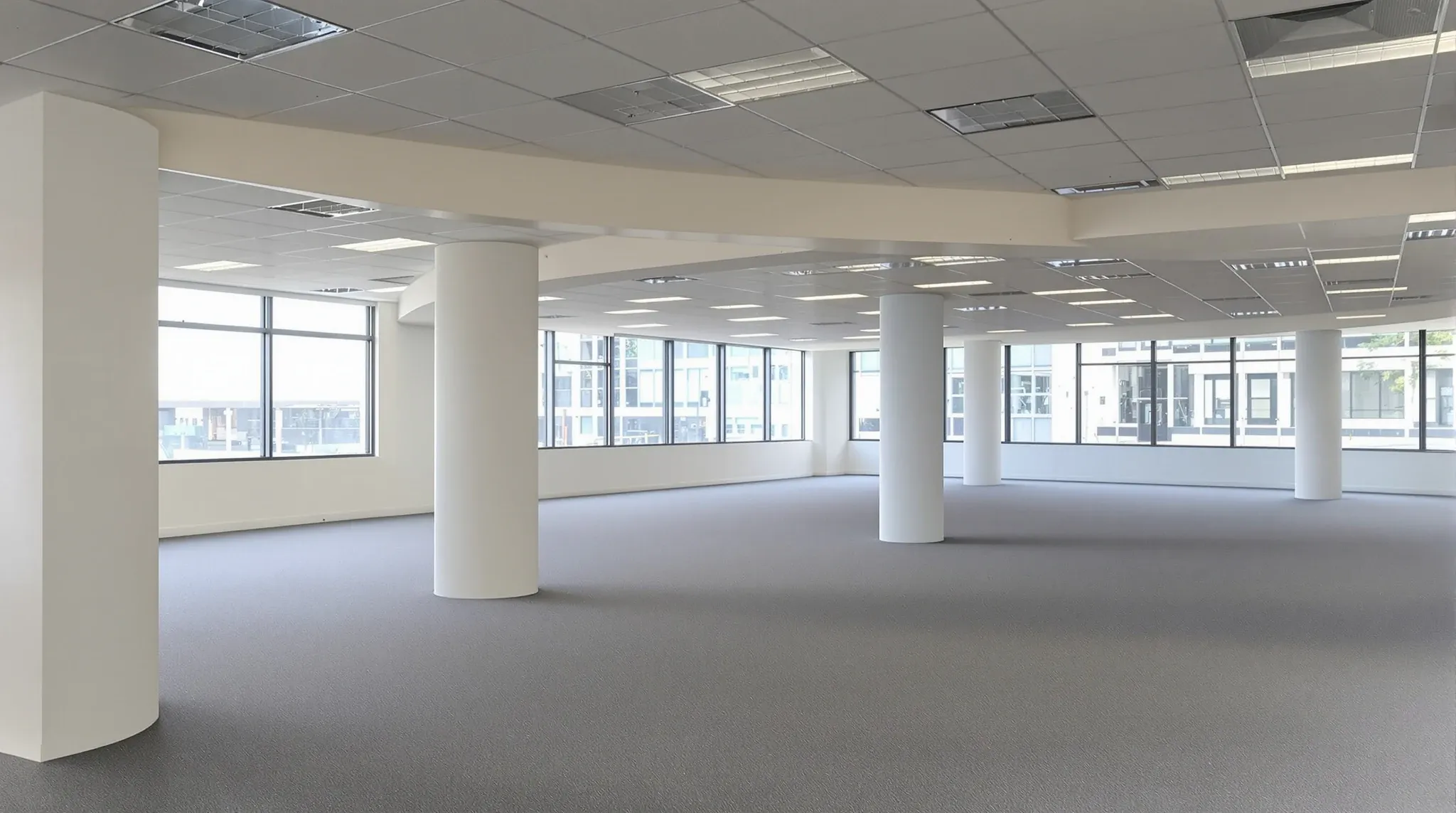 An empty leased office floor where the ceiling steps down into a deep bulkhead along the windows