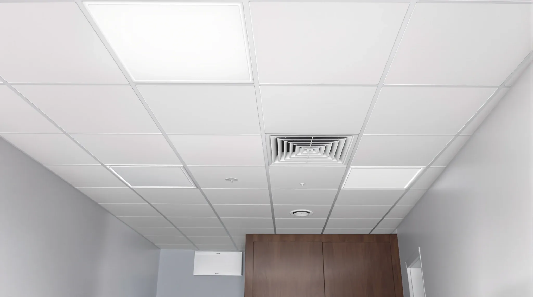 A small GP consulting room with a regular tile ceiling holding a diffuser, a light panel and an exhaust grille