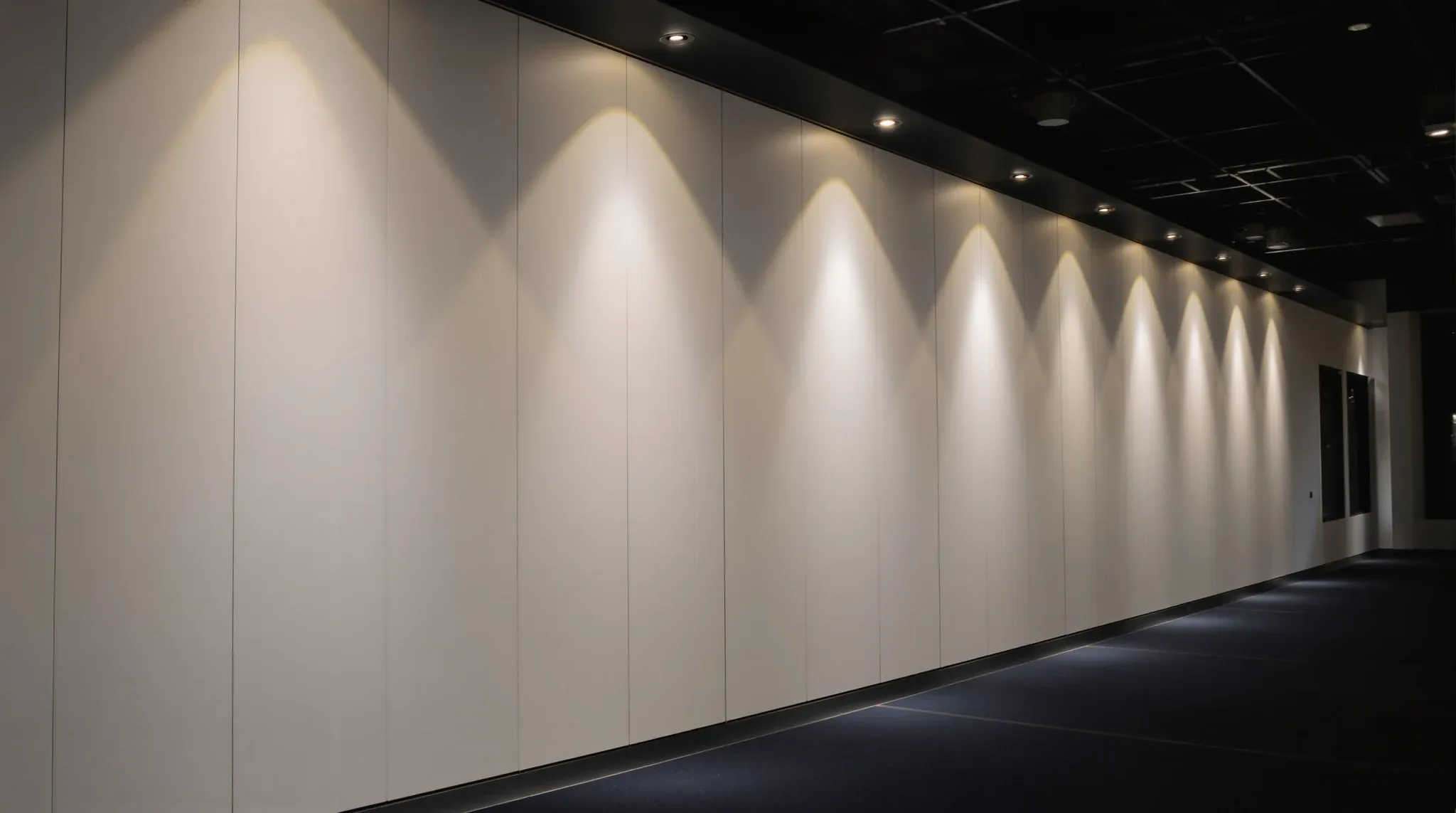 Grazing light on a long painted plasterboard wall at night, showing faint joint lines