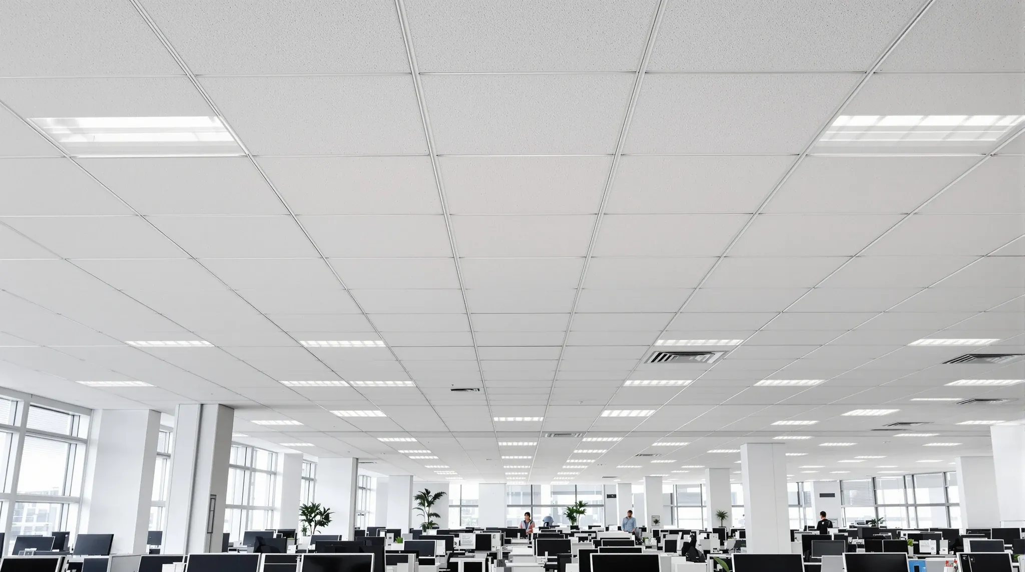 A large open office floor in a newer tower under a long, regular suspended tile ceiling