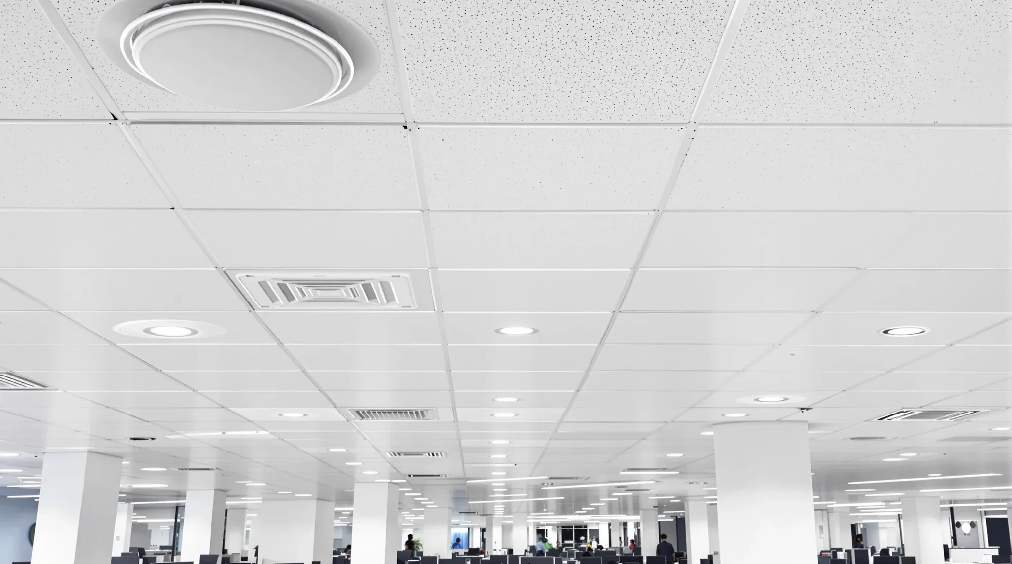 A finished suspended office ceiling with evenly spaced services above a working floor
