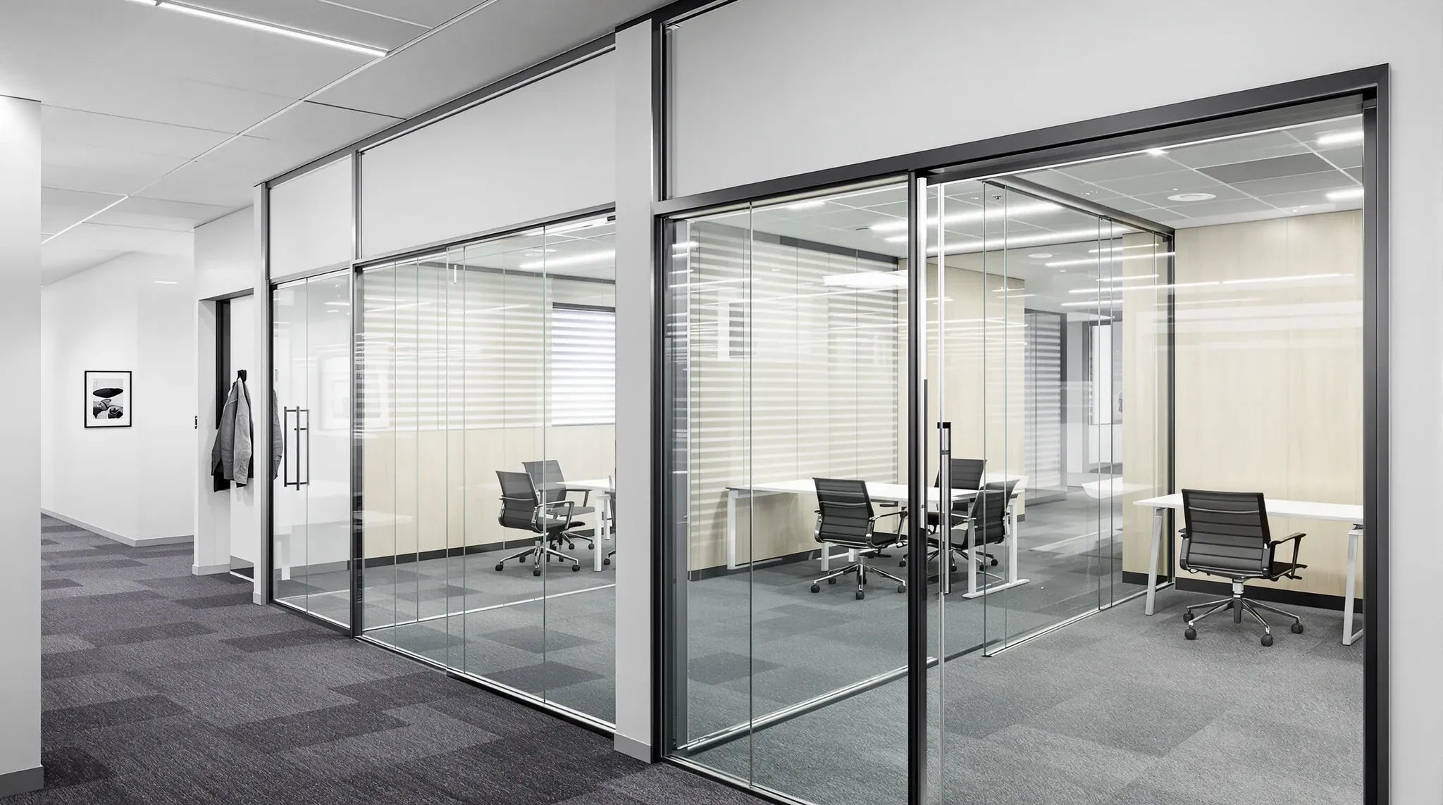 Two small offices along a narrow corridor, one with a hinged glass door open and one with a sliding glass door