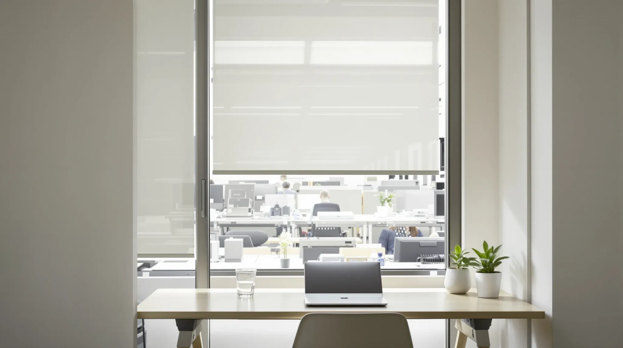 A desk beside an open window with a sheer blind moving in the breeze