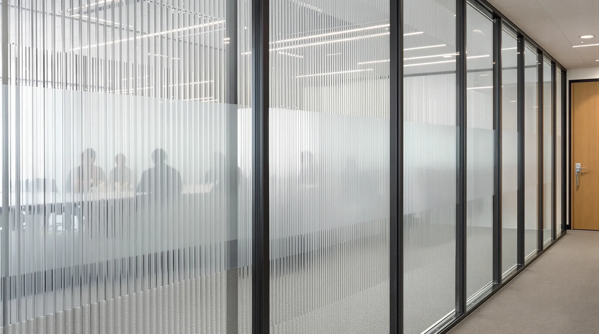 A run of office partition panels in reeded, frosted and banded patterned glass