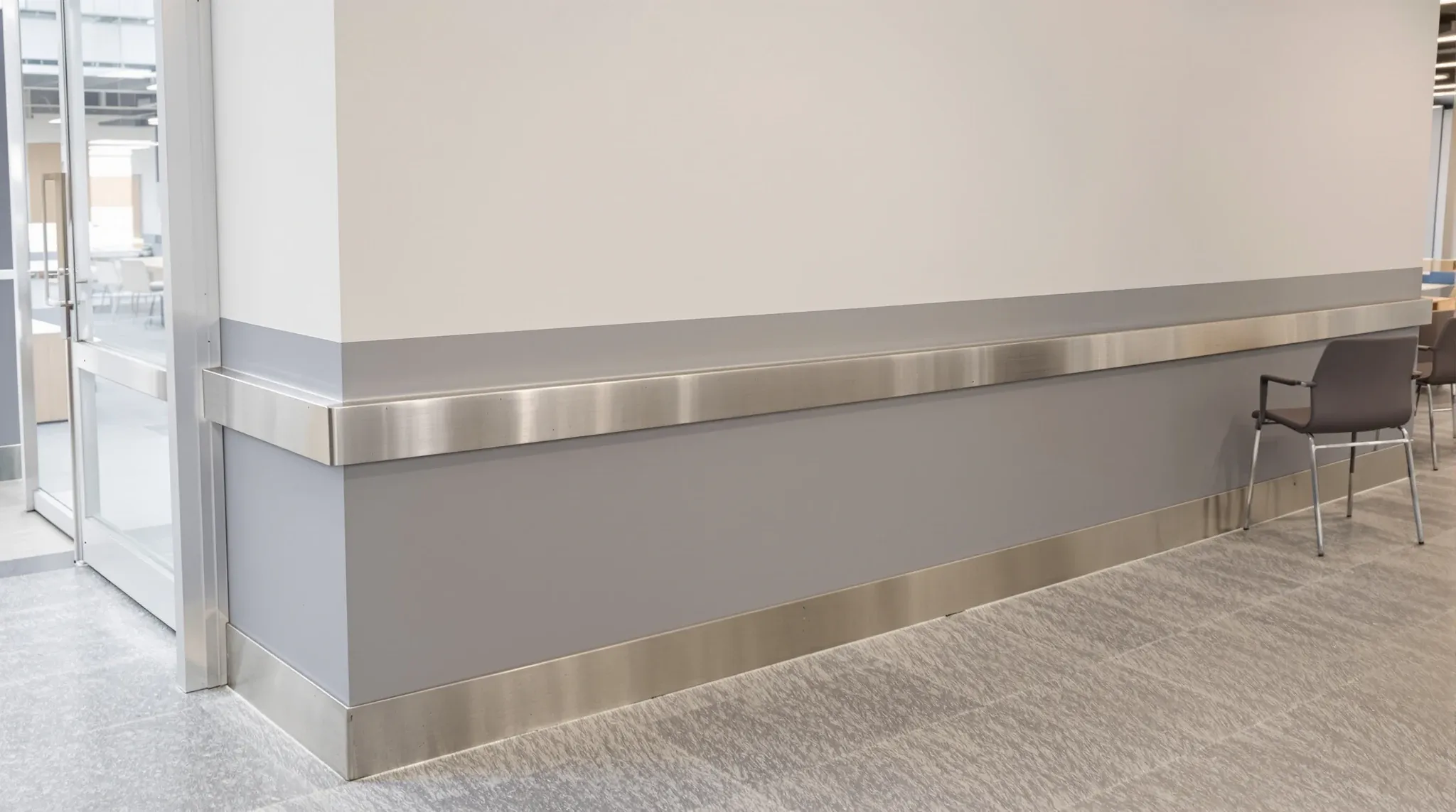 A kitchen entry with a stainless steel corner guard beside a wall scuffed by chairs