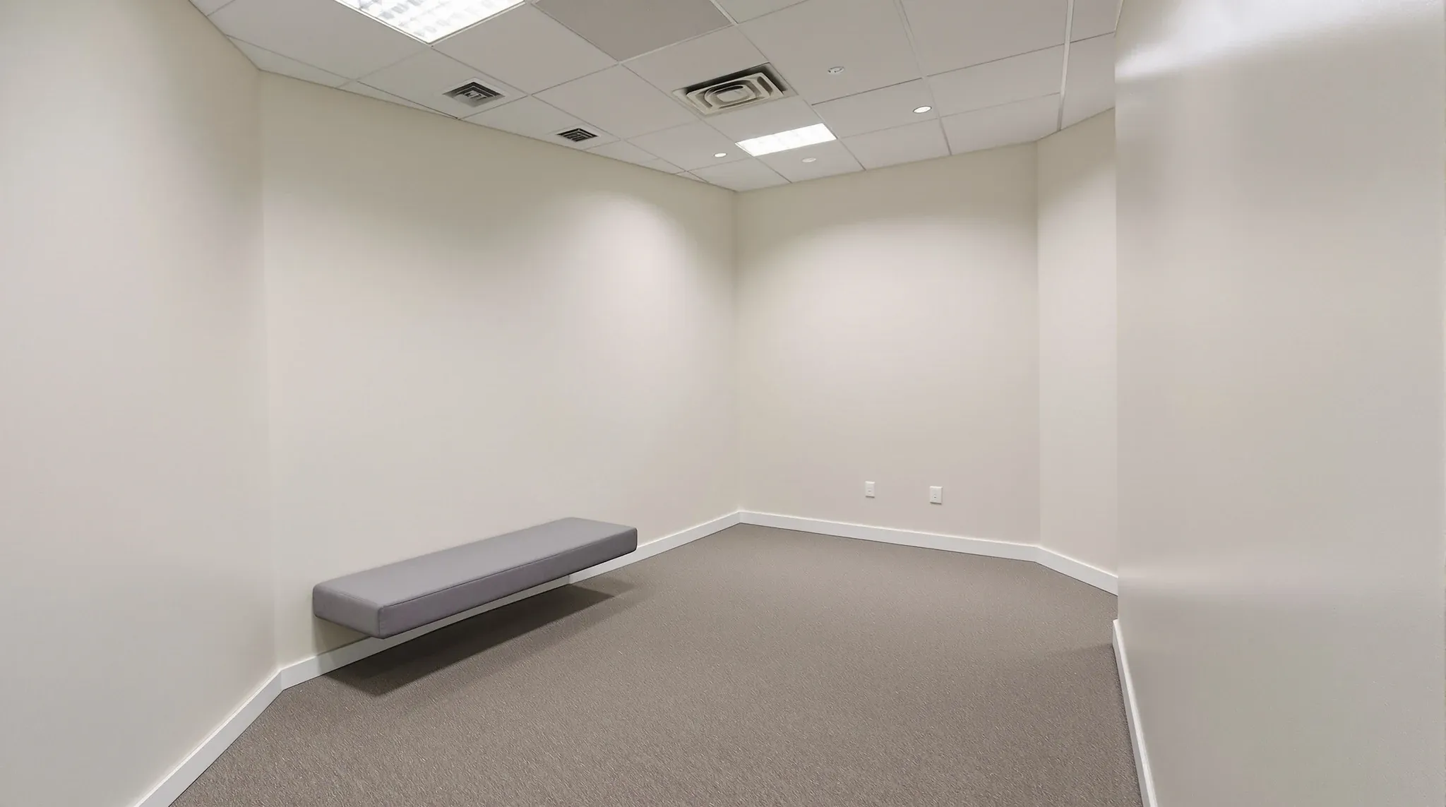 Empty calm small room with soft carpet, low bench, dimmable lighting, no symbols or text