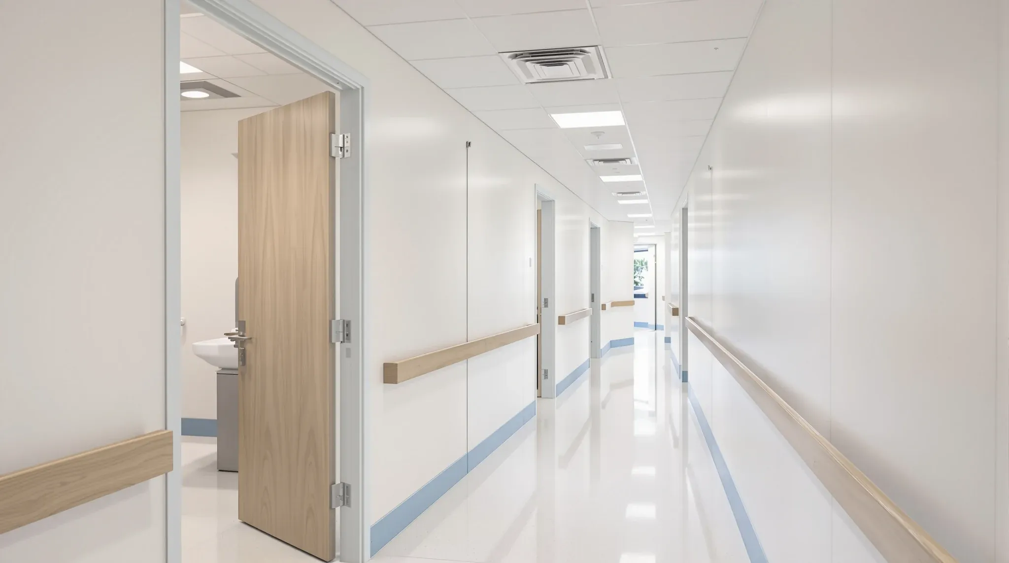 A medical clinic corridor with consulting room doors open, each room fitted with its own hand basin