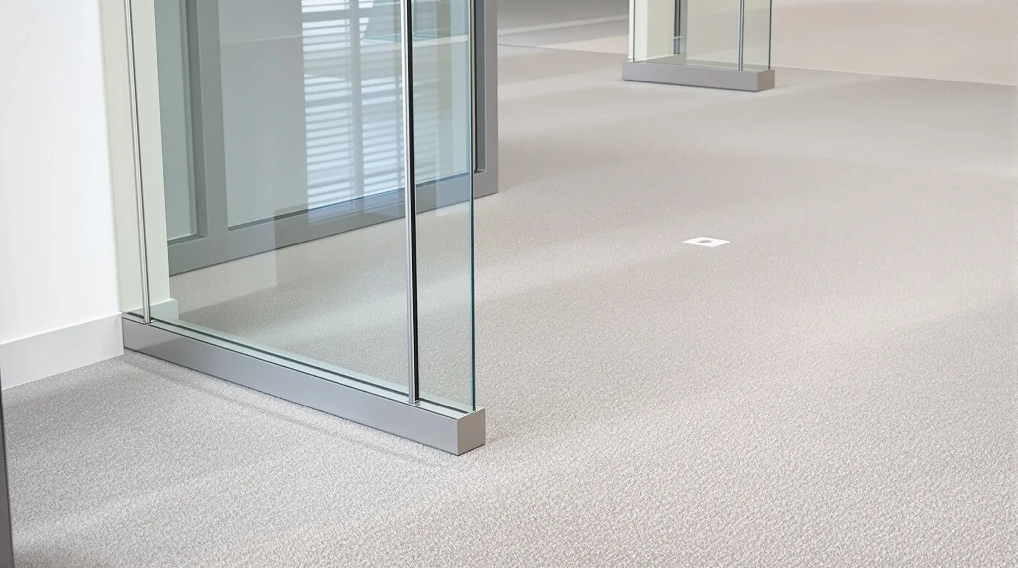 A glass partition base sitting on a raised access floor with a flush outlet