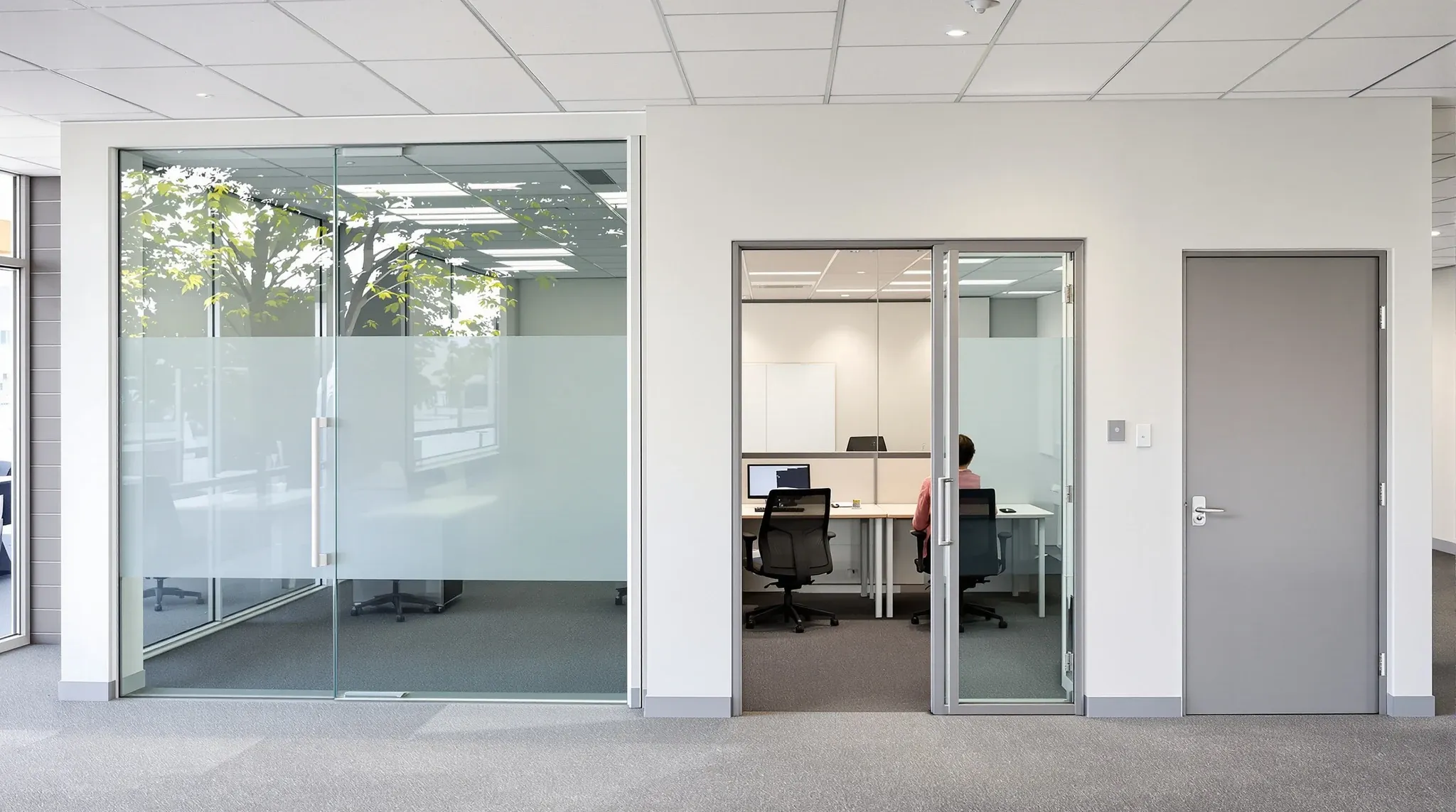 A glass office with a frosted band beside a solid plasterboard room in a small first-floor suburban office