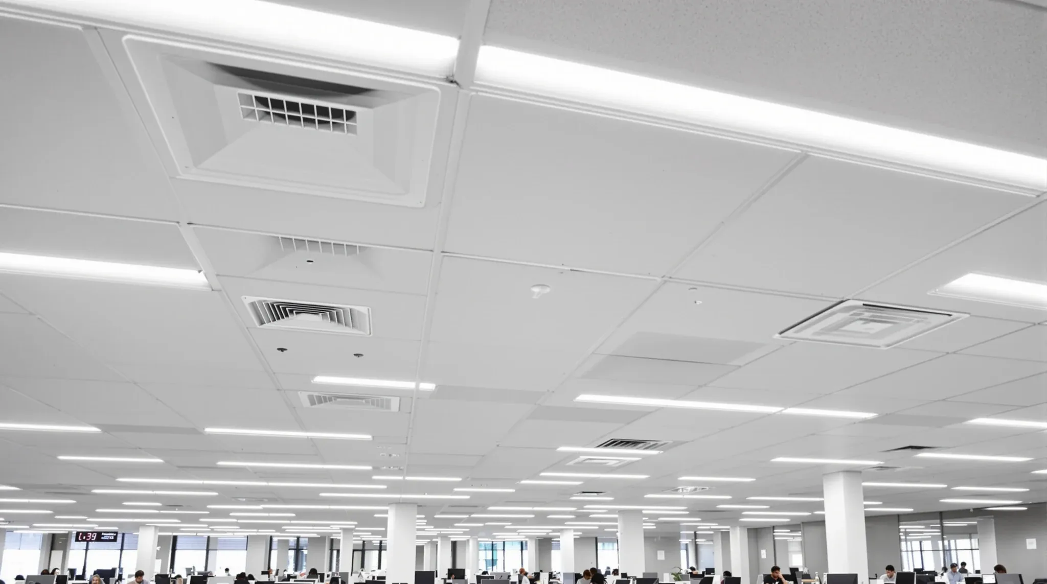 A finished office ceiling with evenly spaced air diffusers restored above a working floor