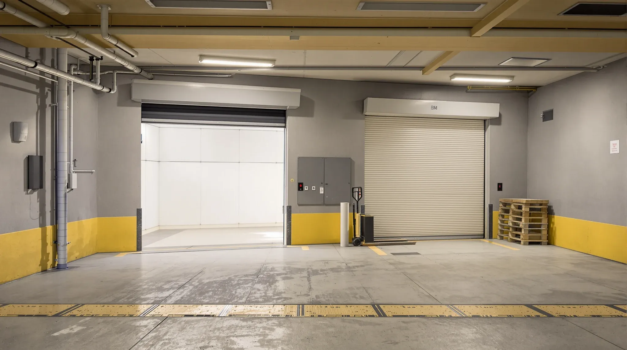 A basement loading dock at dawn with pallets of building materials waiting beside the goods lift