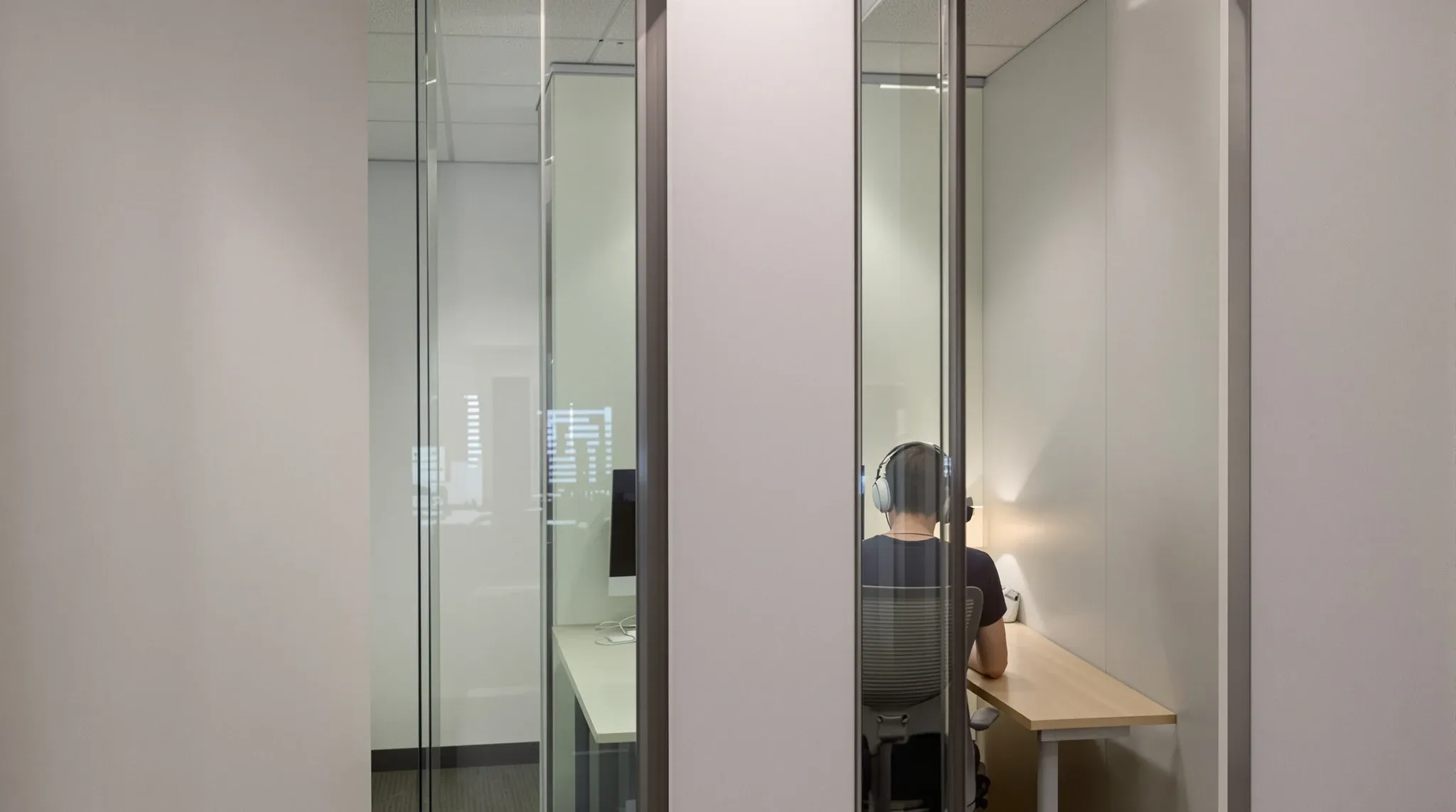 A person seen from behind working in a small enclosed focus room with a closed door