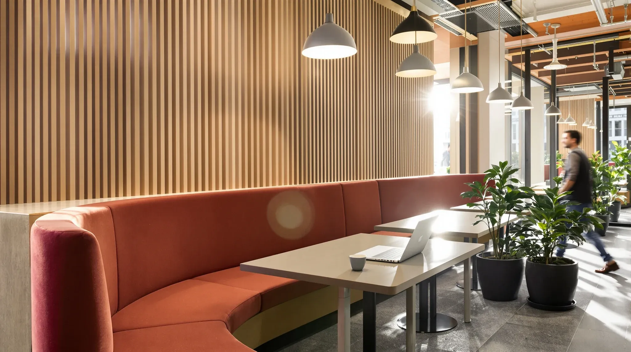A breakout booth by the windows with pendant lights and a timber acoustic wall