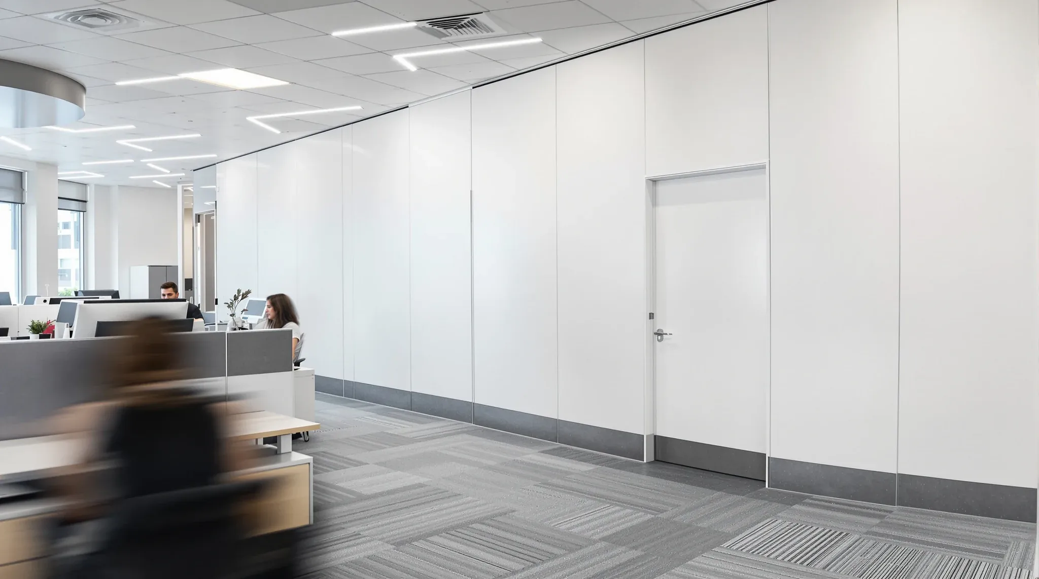 Staff working in an office while the far end of the floor is closed off behind a temporary white wall