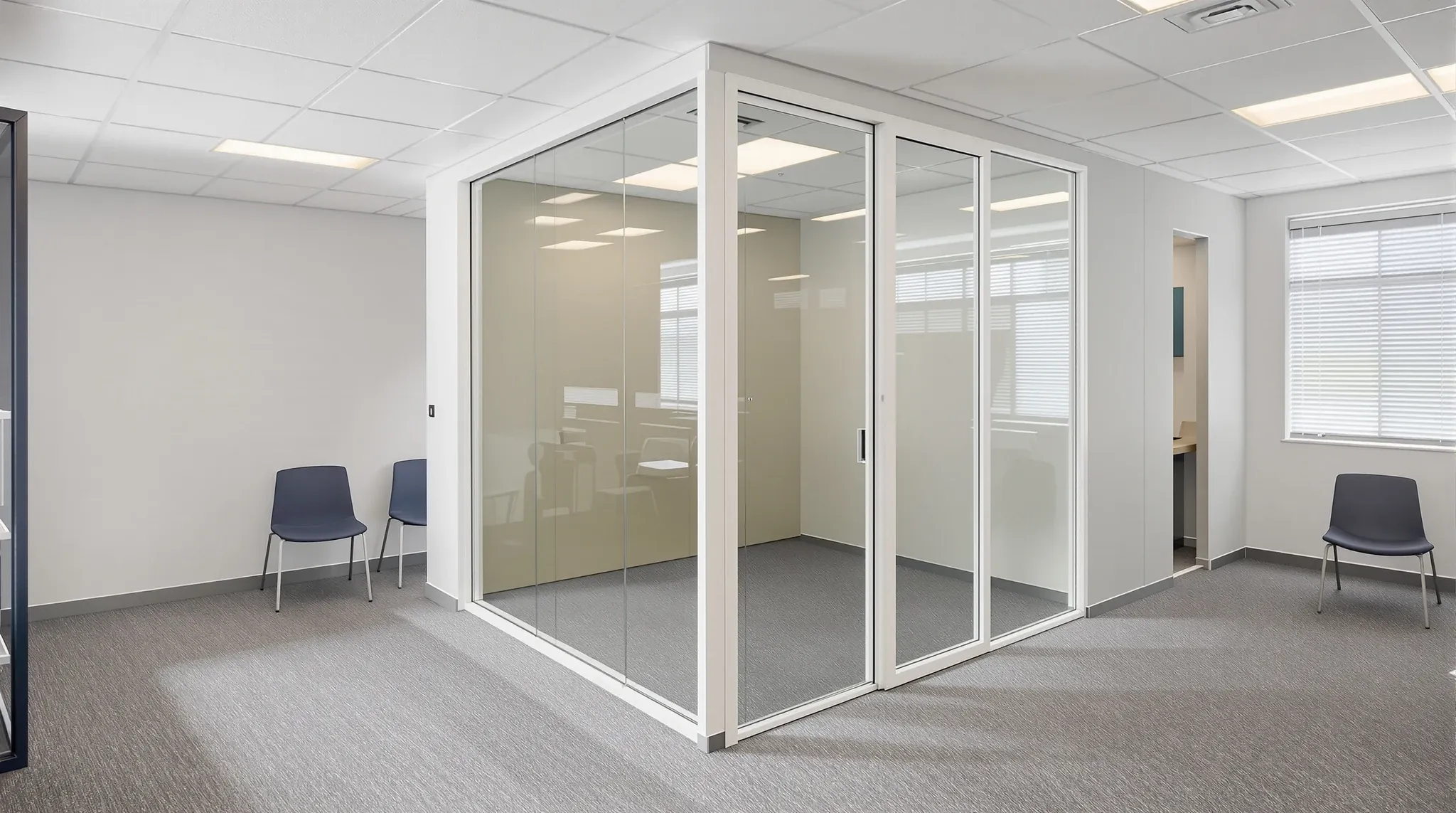 A new white-framed glass office in a small older office beside a staff kitchenette