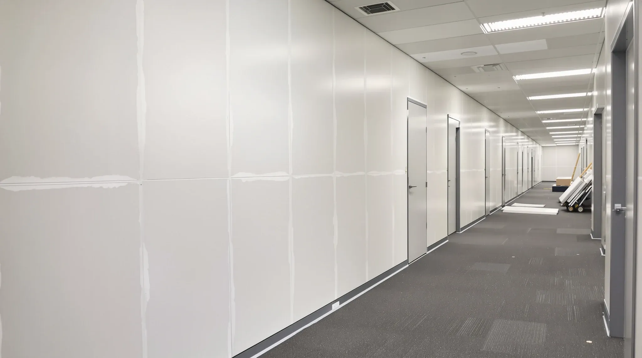 Office partition walls newly overboarded, with joints set and sanded ready for paint