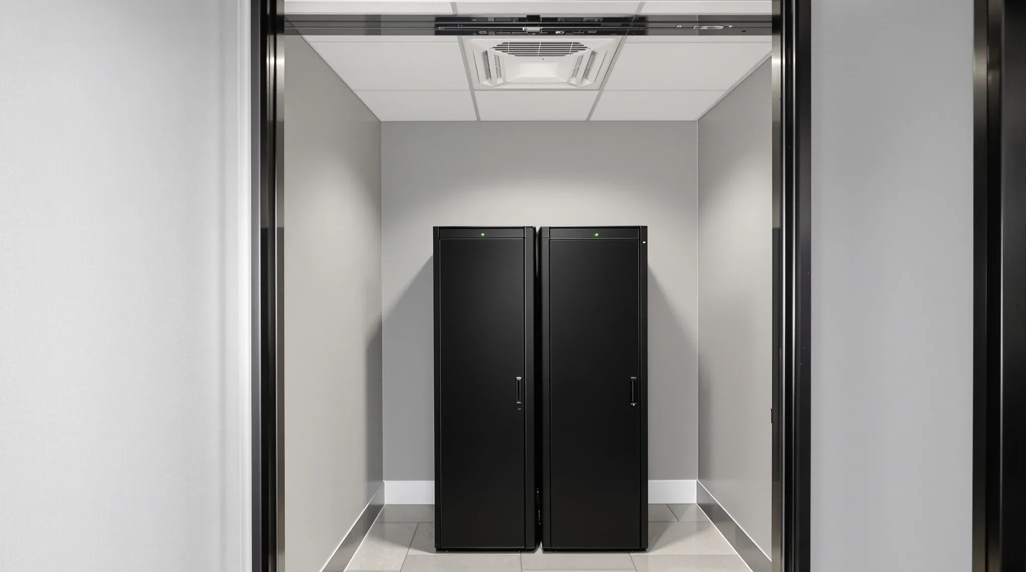 A tidy comms room with two black equipment racks against plain grey painted plasterboard walls