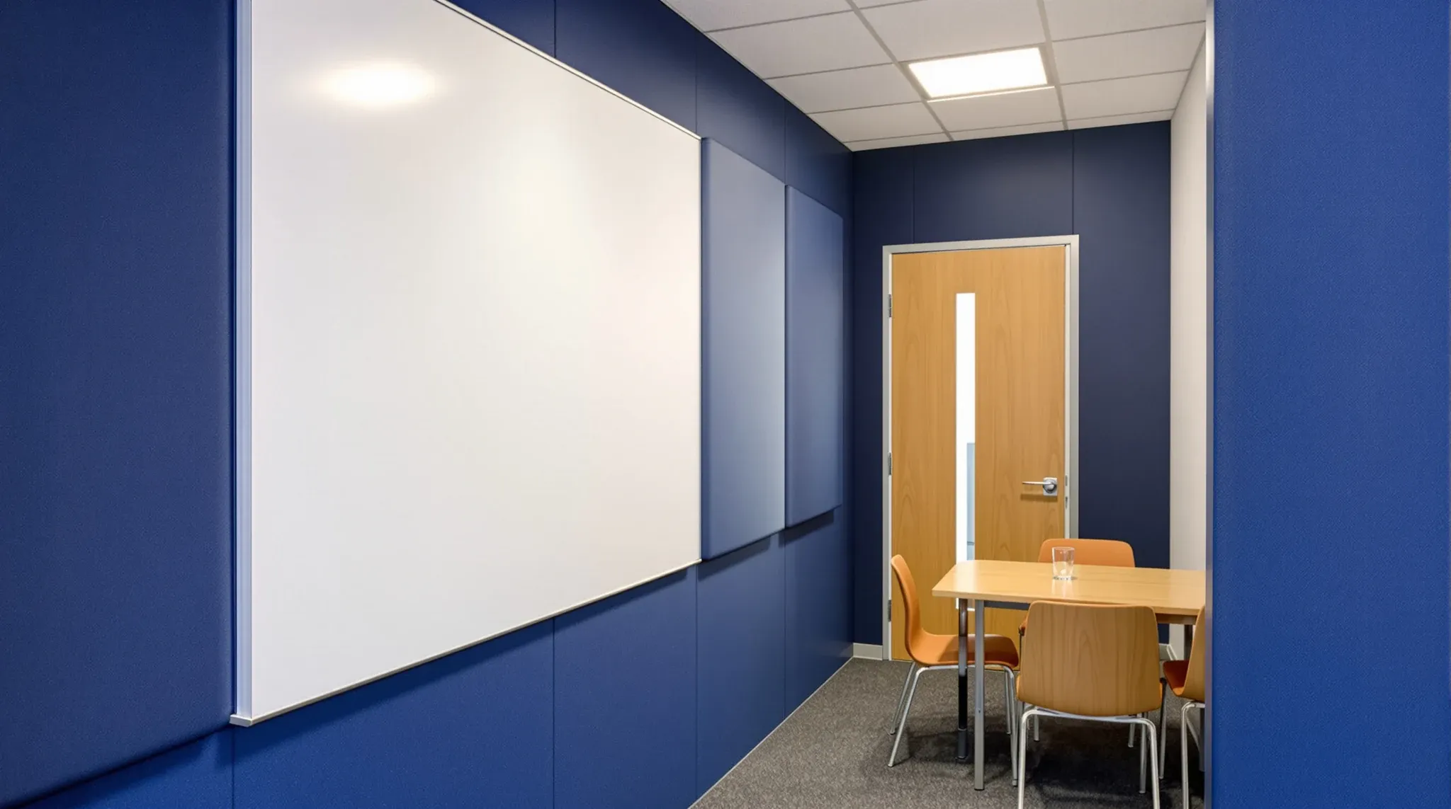 Inside a small enclosed meeting room with fabric acoustic panels, thick carpet and a closed solid door