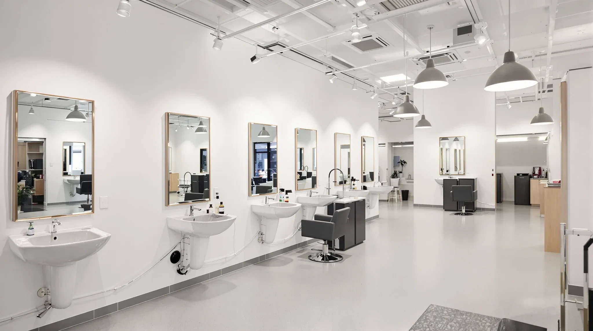 Empty finished salon with wall mirrors, backwash basins, pendant lighting, no branding